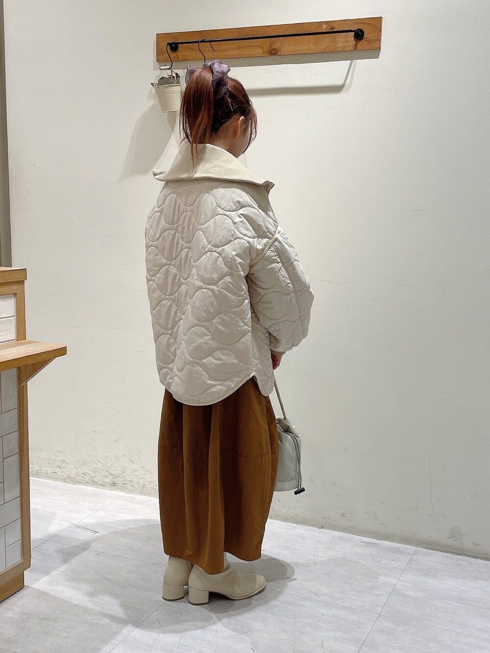 ブラウン系のニット/セーター、ホワイト系のノーカラージャケット、イエロー系のスカートを着用したレディースの秋コーディネートの3枚目の写真