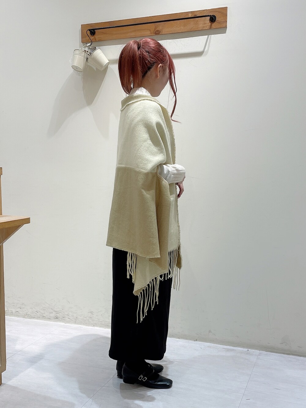 ホワイト系のニット/セーター、ブラック系のスカート、イエロー系のストール/ショールを着用したレディースの秋コーディネートの2枚目の写真