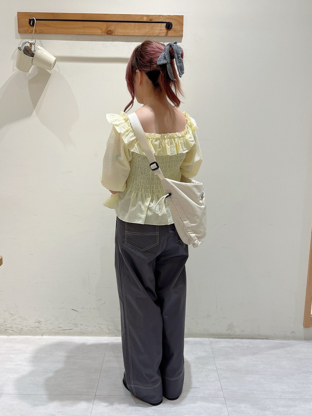 イエロー系のシャツ/ブラウス、ブラック系のパンツ、ホワイト系のハンドバッグを着用したレディースの春コーディネートの3枚目の写真