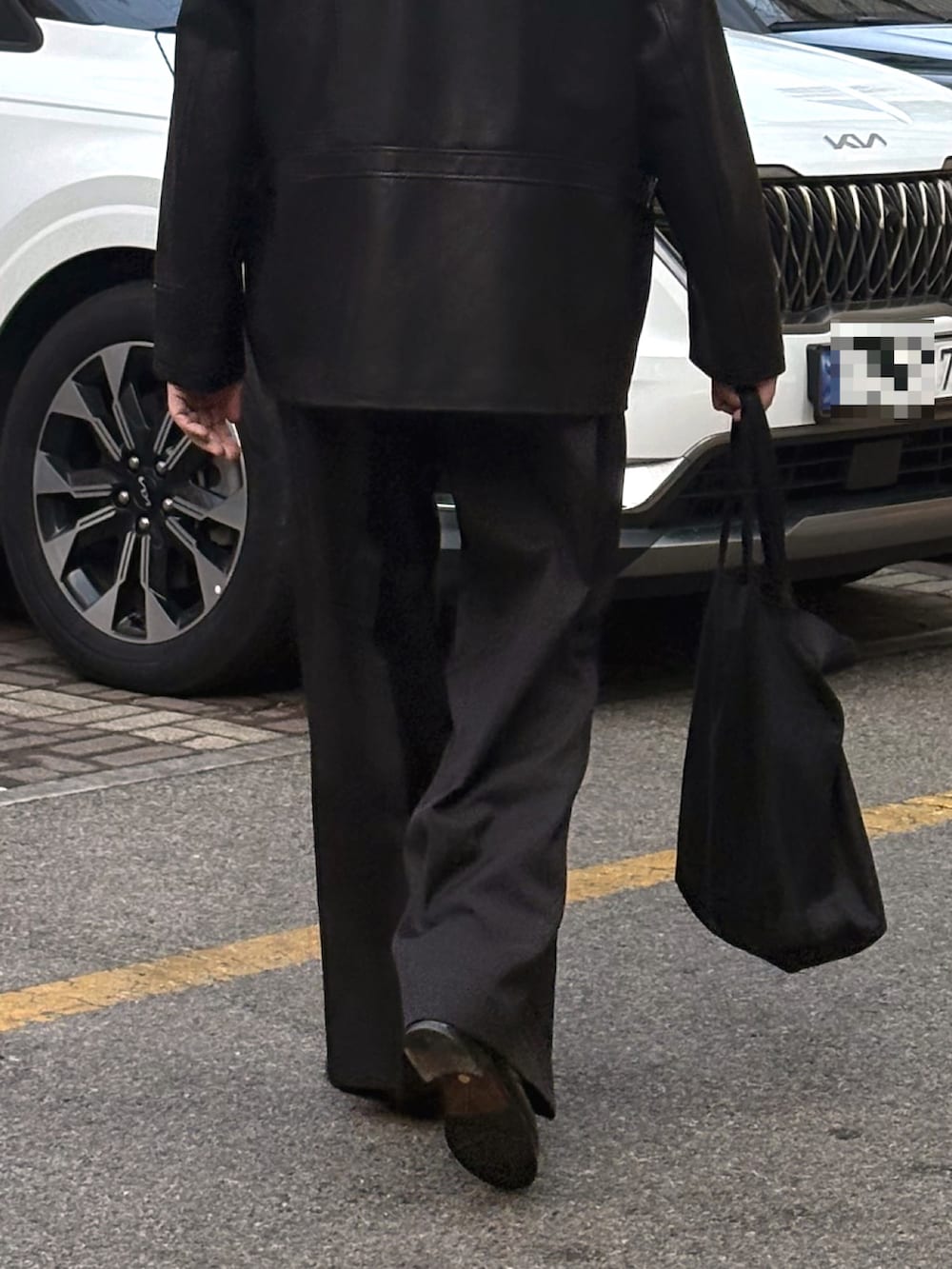 ブラック系のスラックス、ブラック系のドレスシューズ、ブラック系のトートバッグを着用したメンズの春コーディネートの2枚目の写真