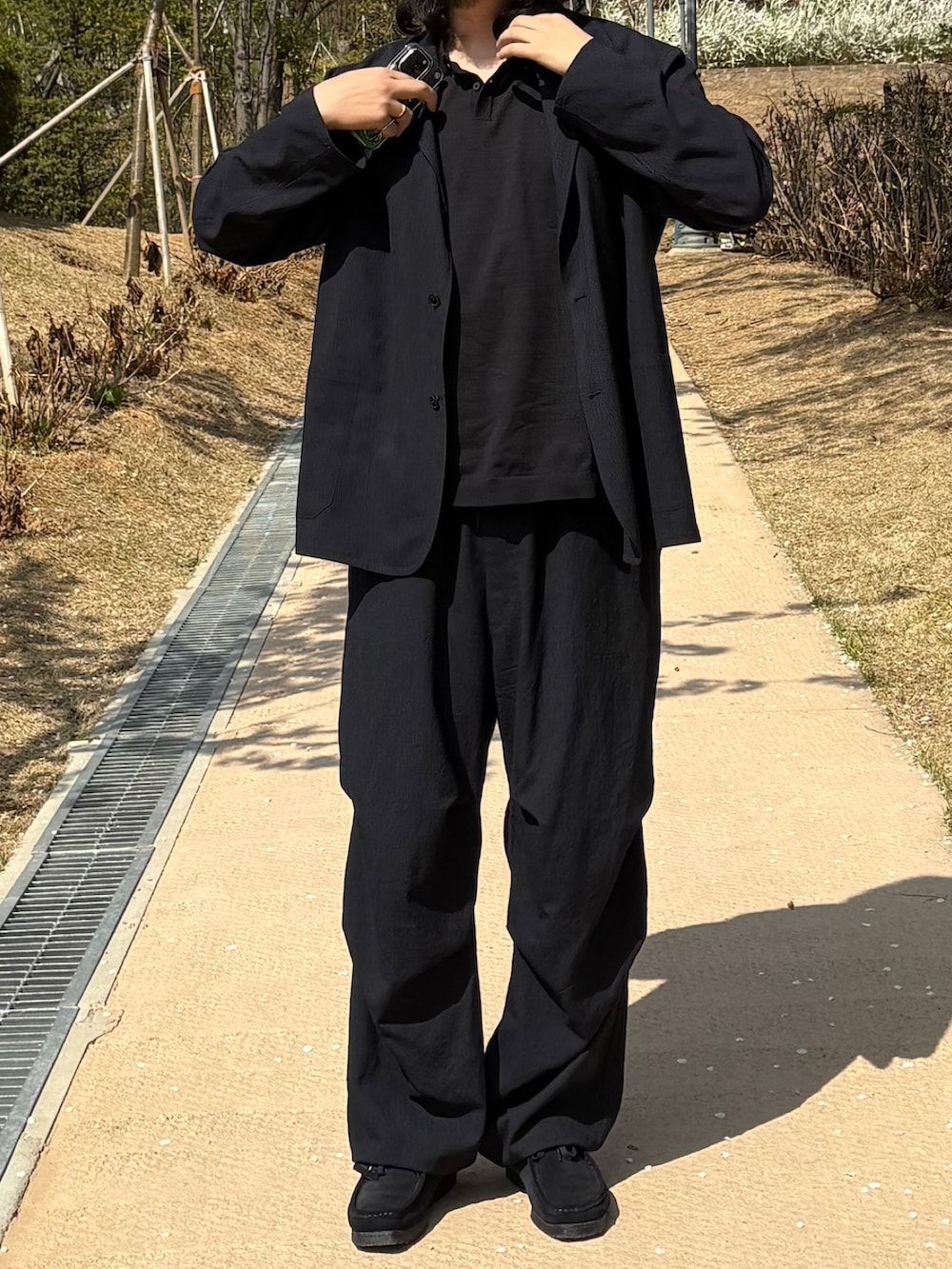 ブラック系のテーラードジャケット、ブラック系のスラックス、ブルー系のその他シューズを着用したメンズの春コーディネートの3枚目の写真