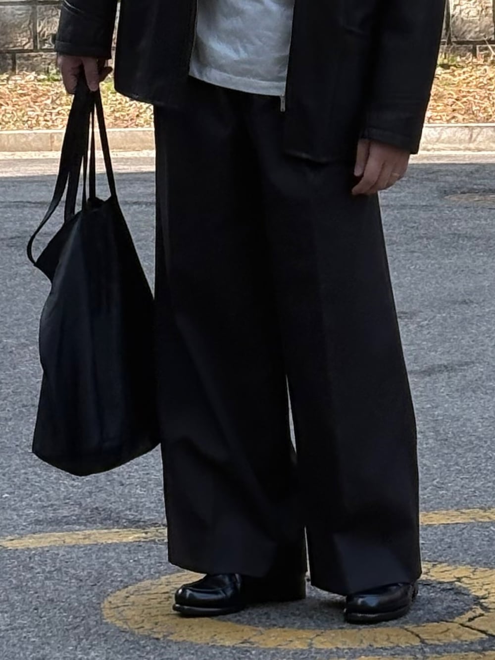 ブラック系のスラックス、ブラック系のドレスシューズ、ブラック系のトートバッグを着用したメンズの春コーディネートの4枚目の写真