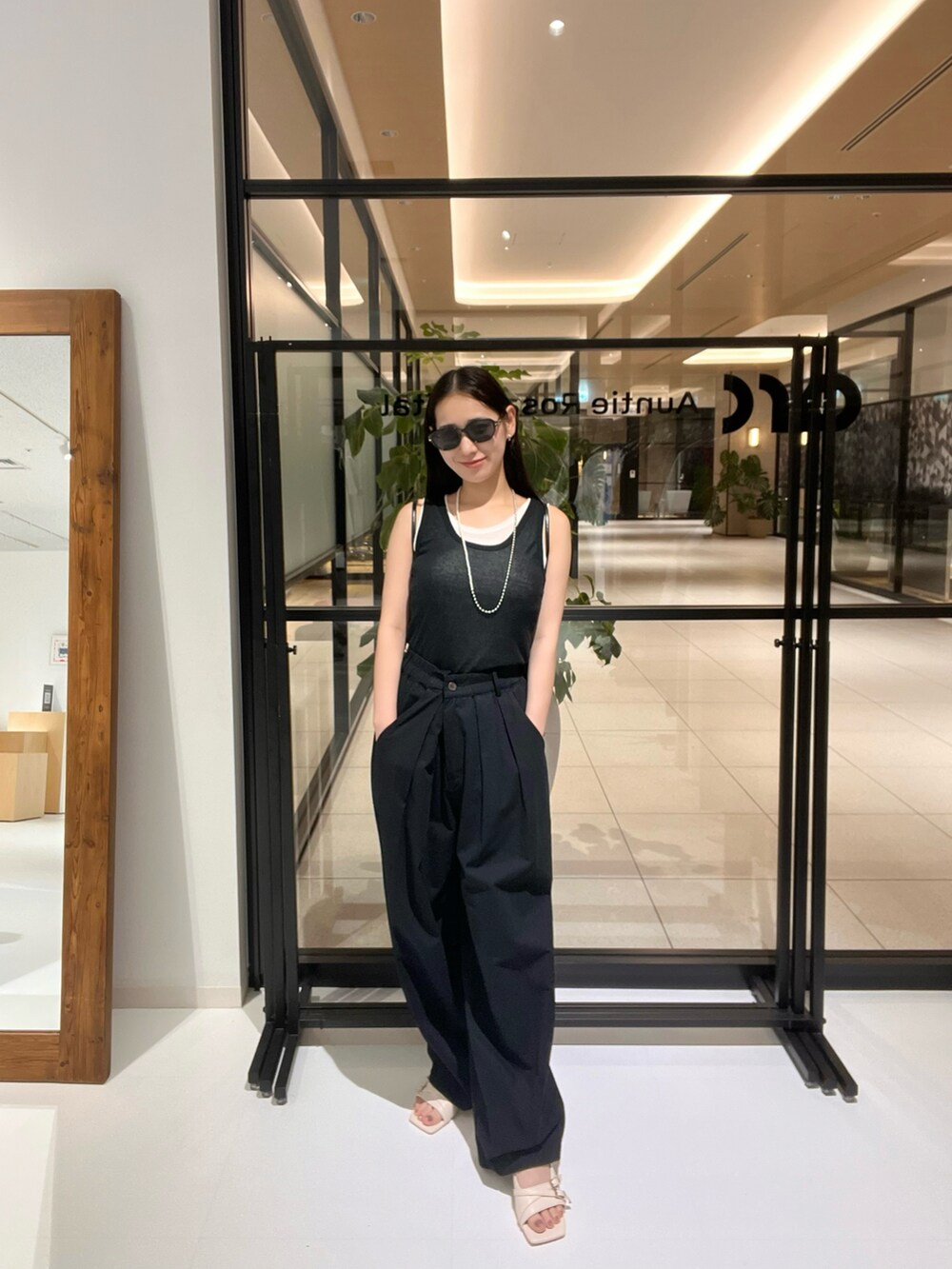 ホワイト系のサンダル、ブラック系のタンクトップ、シルバー系のネックレスを着用したレディースの夏コーディネートの2枚目の写真