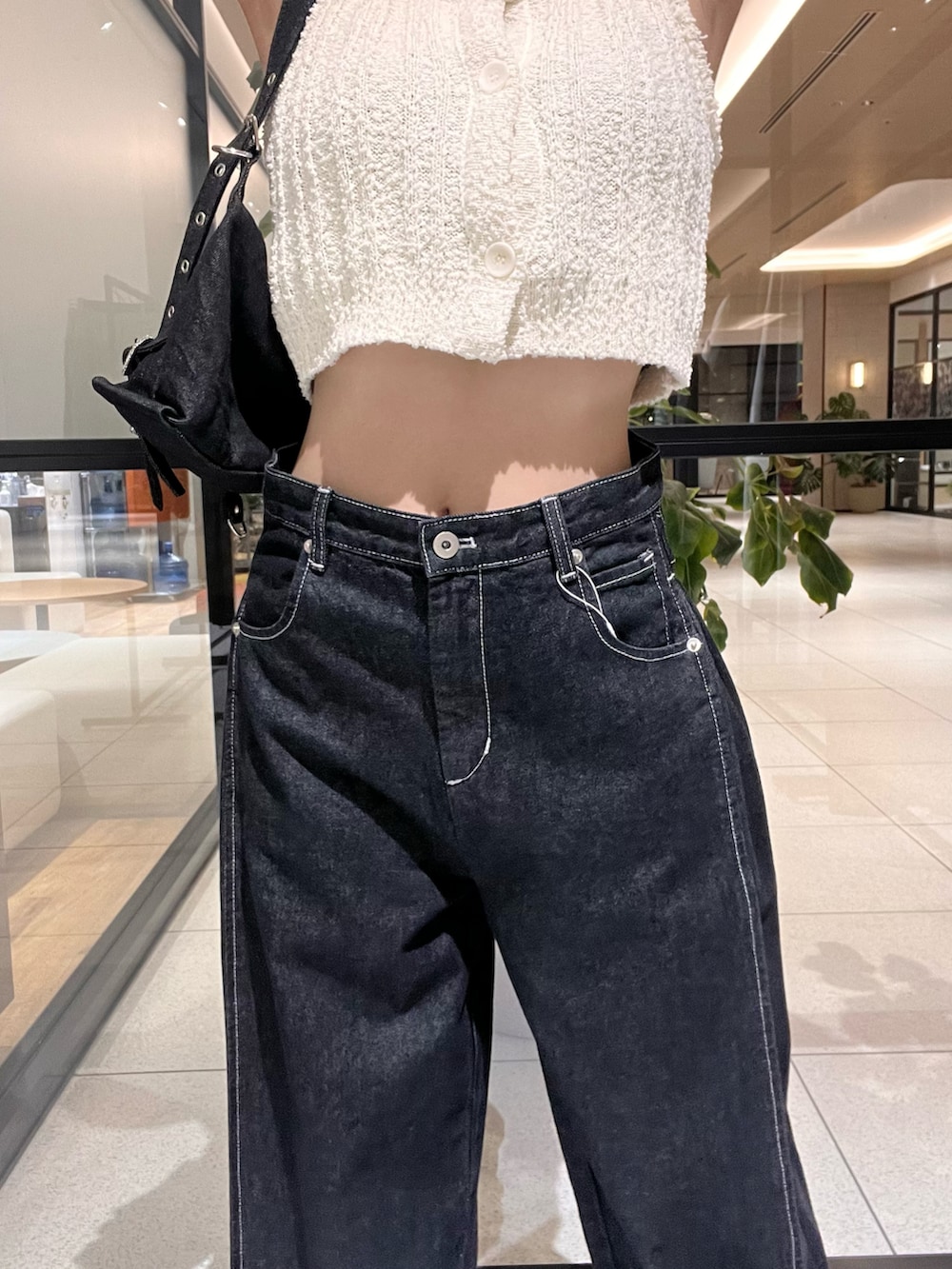 ホワイト系のトップス、ブラック系のショルダーバッグ、ブラック系のデニムパンツを着用したレディースの春コーディネートの2枚目の写真