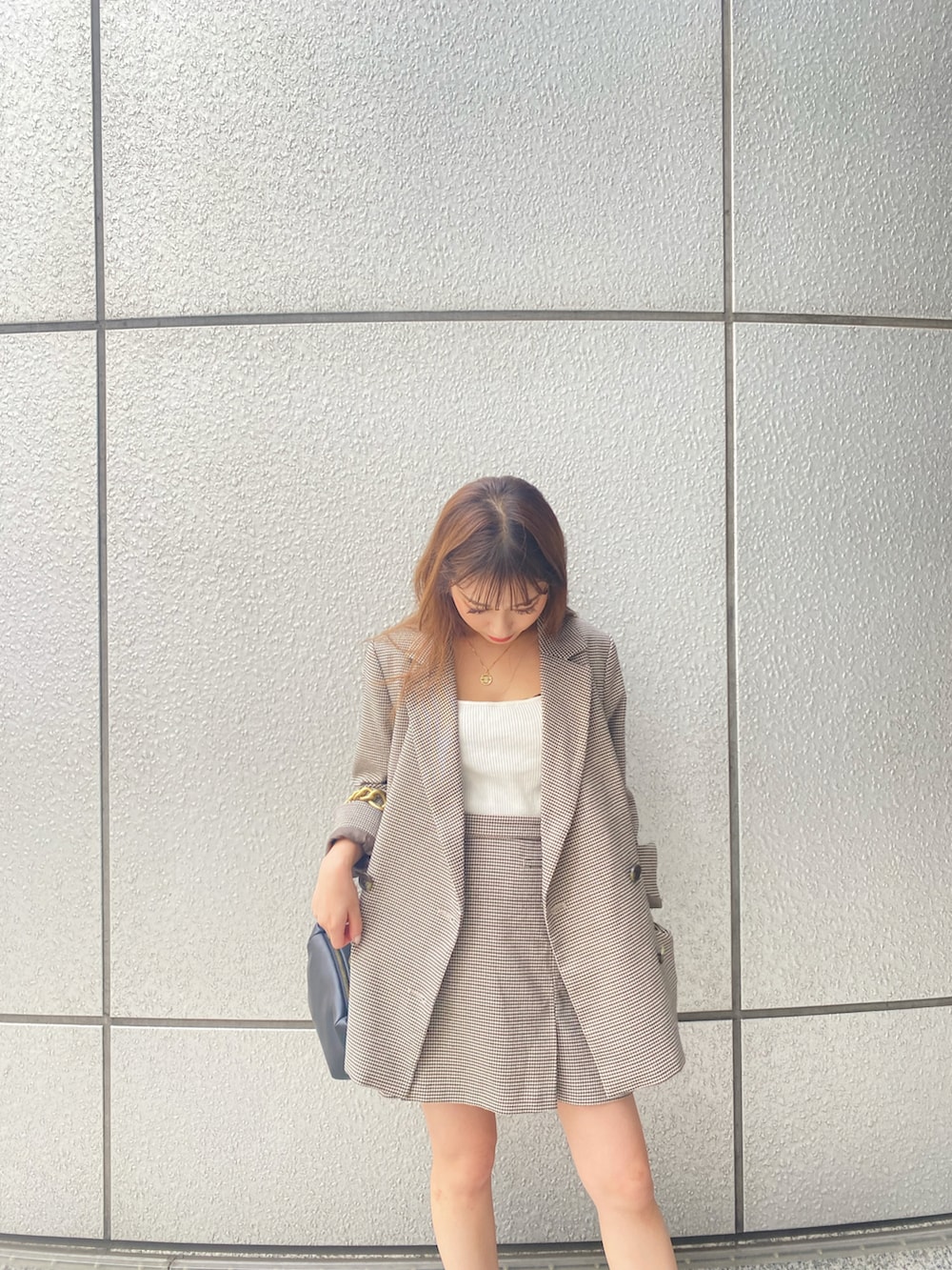 ベージュ系のテーラードジャケット、ベージュ系のスカート、ブラック系のハンドバッグを着用したレディースの秋コーディネートの3枚目の写真