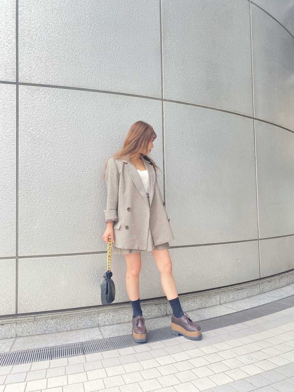 ベージュ系のテーラードジャケット、ベージュ系のスカート、ブラック系のハンドバッグを着用したレディースの秋コーディネートの2枚目の写真