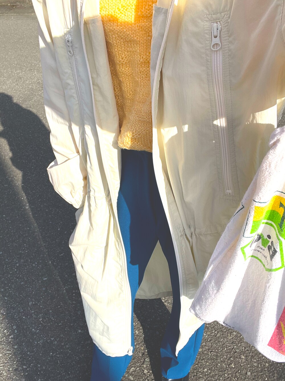 ブルー系のスラックス、イエロー系のニット/セーター、ホワイト系のジャケット/アウターを着用したレディースの冬コーディネートの2枚目の写真