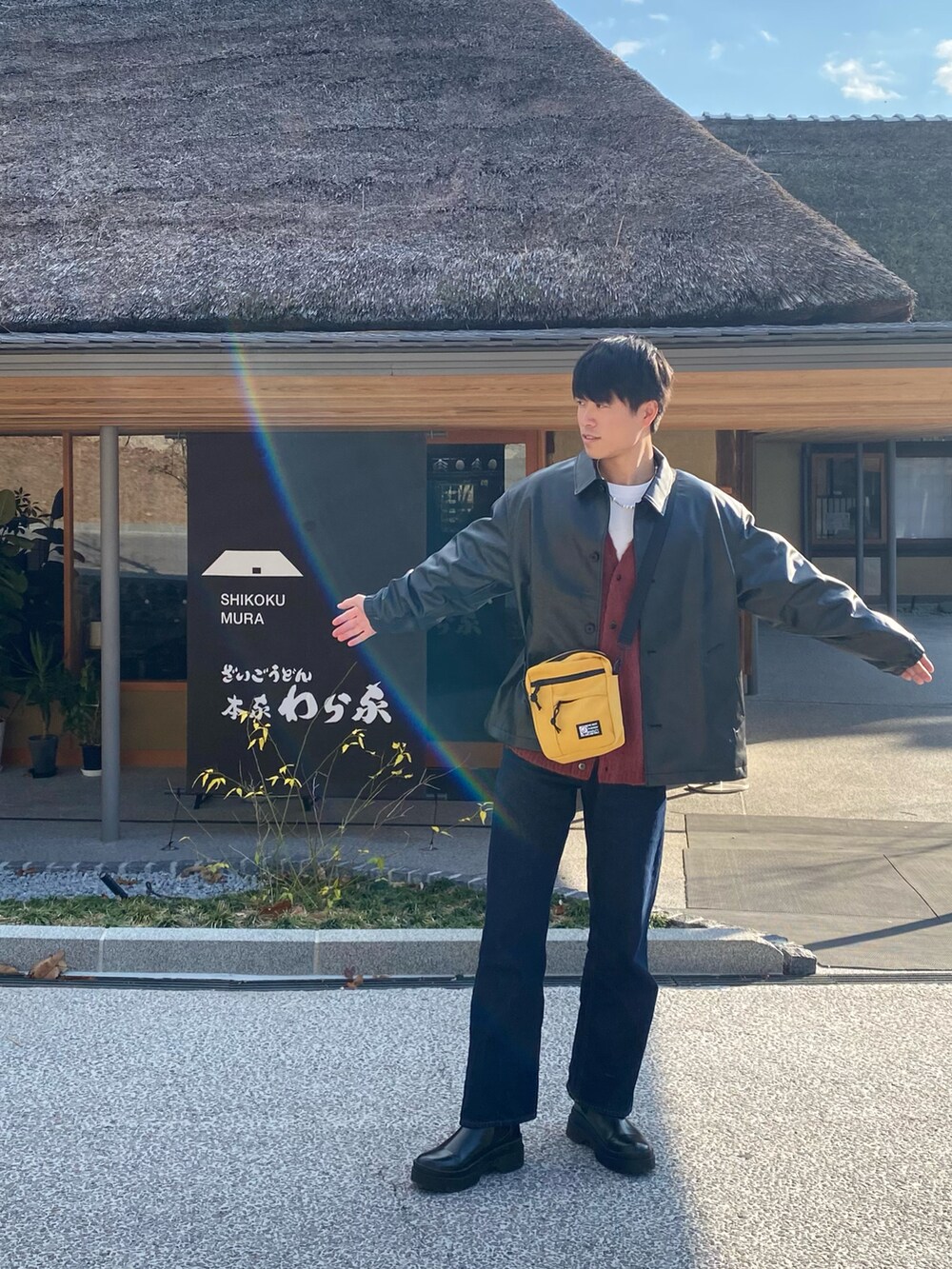 ブラック系のブーツ、オレンジ系のカーディガン/ボレロ、ブラック系のジャケット/アウターを着用したメンズの冬コーディネートの3枚目の写真