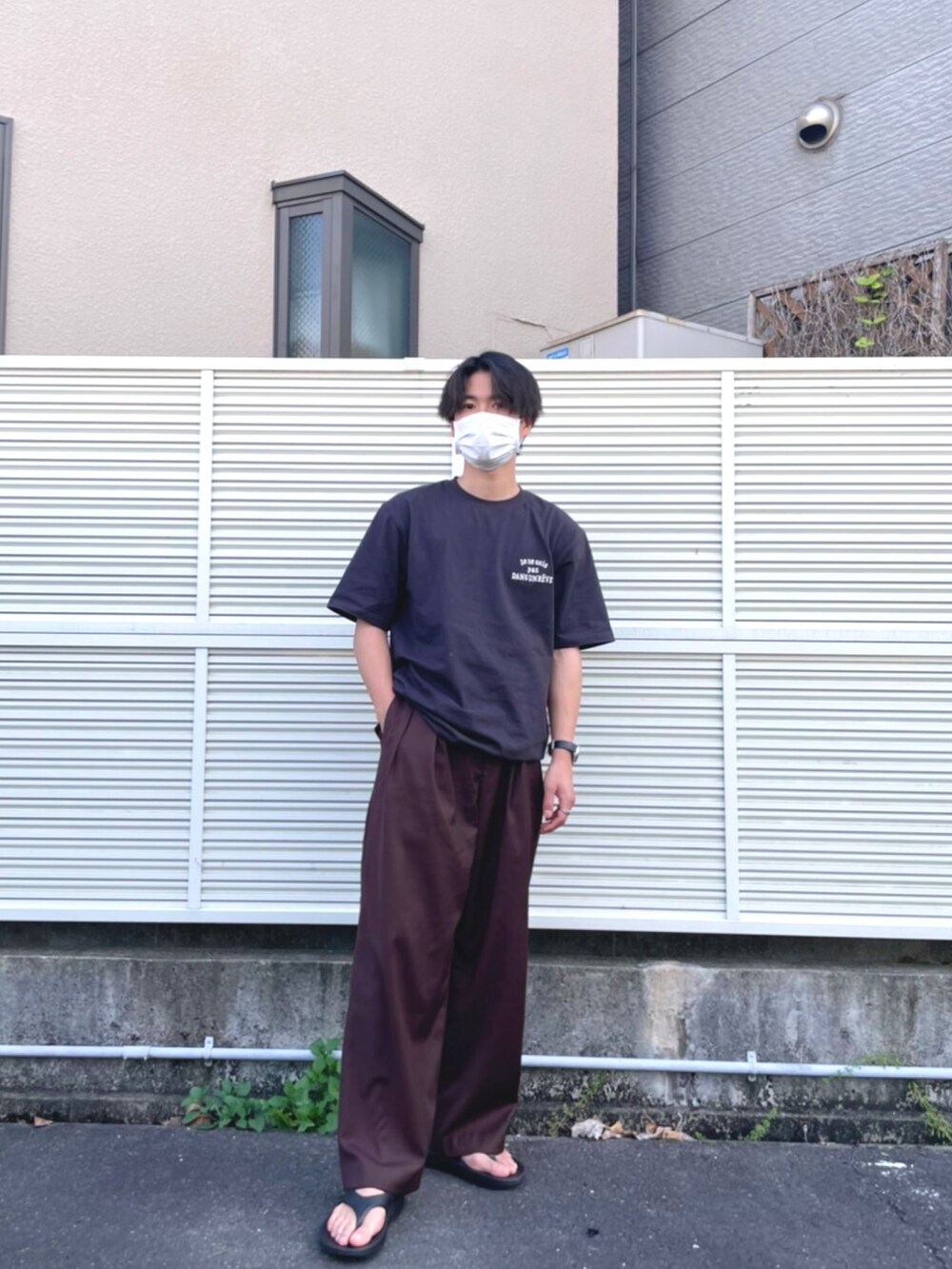 ブラック系のサンダル、ブラウン系のスラックス、ブラック系のTシャツ/カットソーを着用したメンズの春コーディネートの2枚目の写真