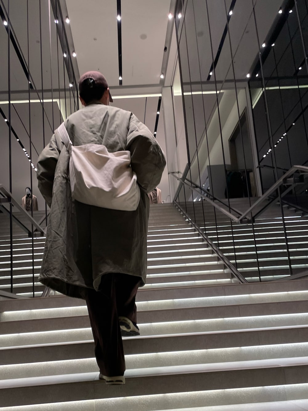 ブラック系のモッズコート、ブルー系のスニーカー、ブラウン系のスラックスを着用したメンズの冬コーディネートの2枚目の写真