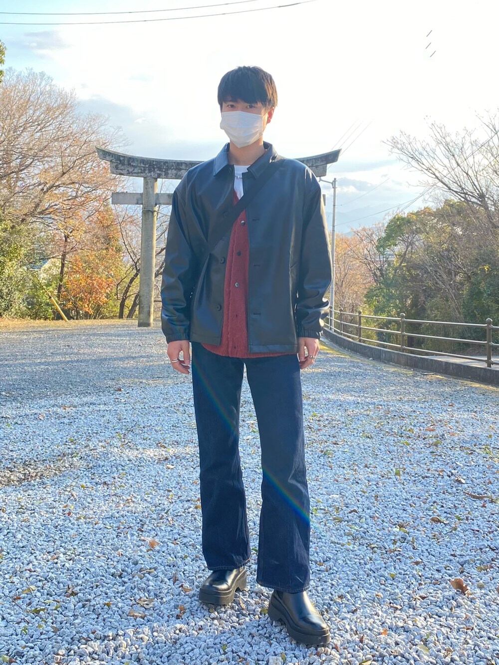 ブラック系のブーツ、オレンジ系のカーディガン/ボレロ、ブラック系のジャケット/アウターを着用したメンズの冬コーディネートの2枚目の写真