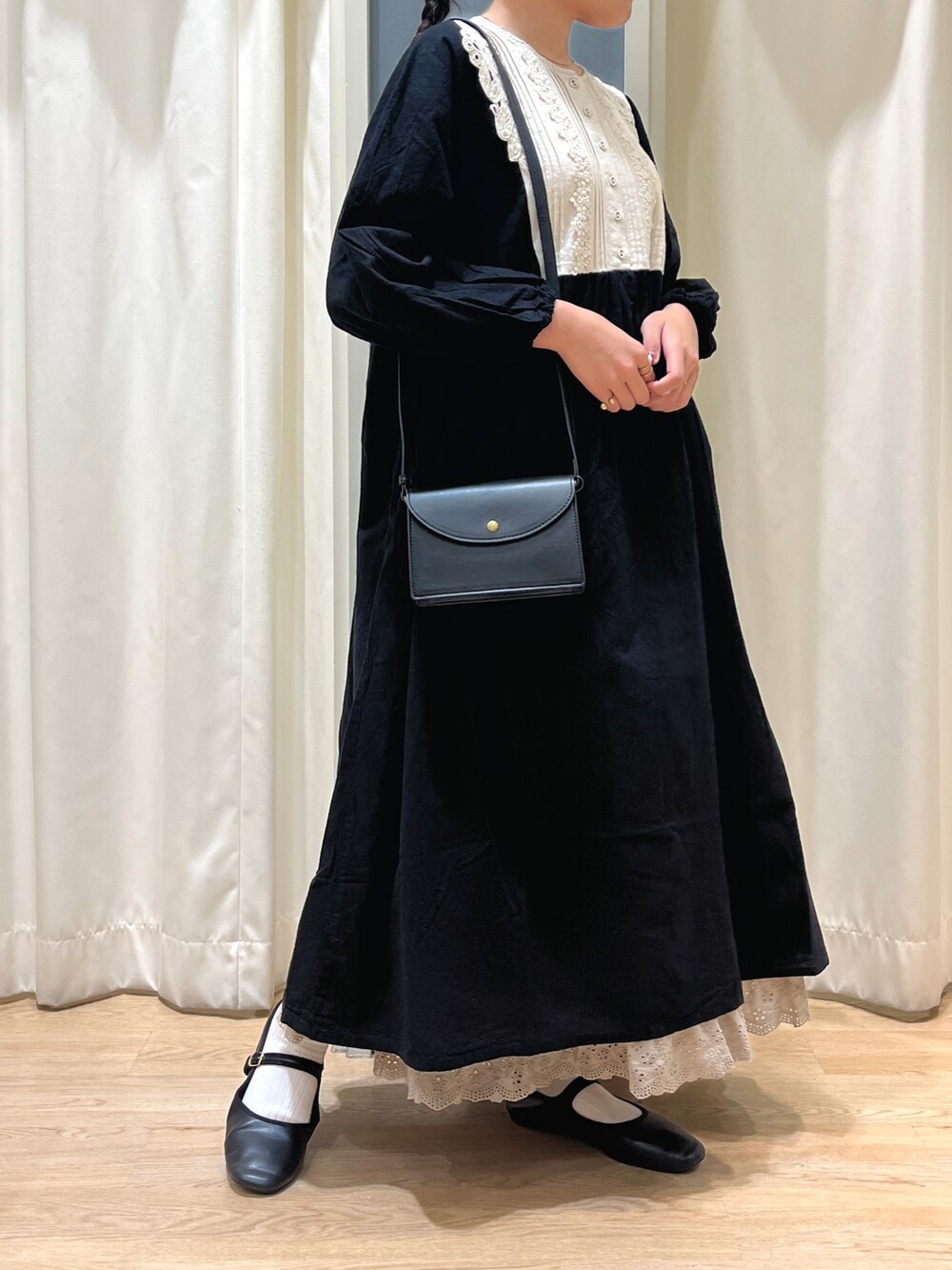 ブラック系のパンプス、ホワイト系のスカート、ベージュ系のショルダーバッグを着用したレディースの秋コーディネートの2枚目の写真