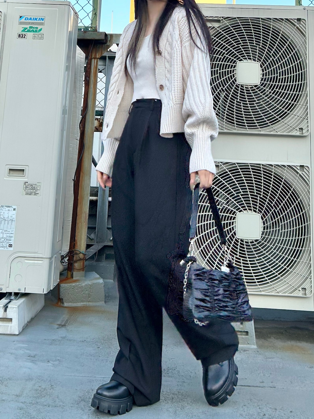 ブラック系のスラックス、ホワイト系のカーディガン/ボレロ、ブラック系のブーツを着用したレディースの秋コーディネートの2枚目の写真