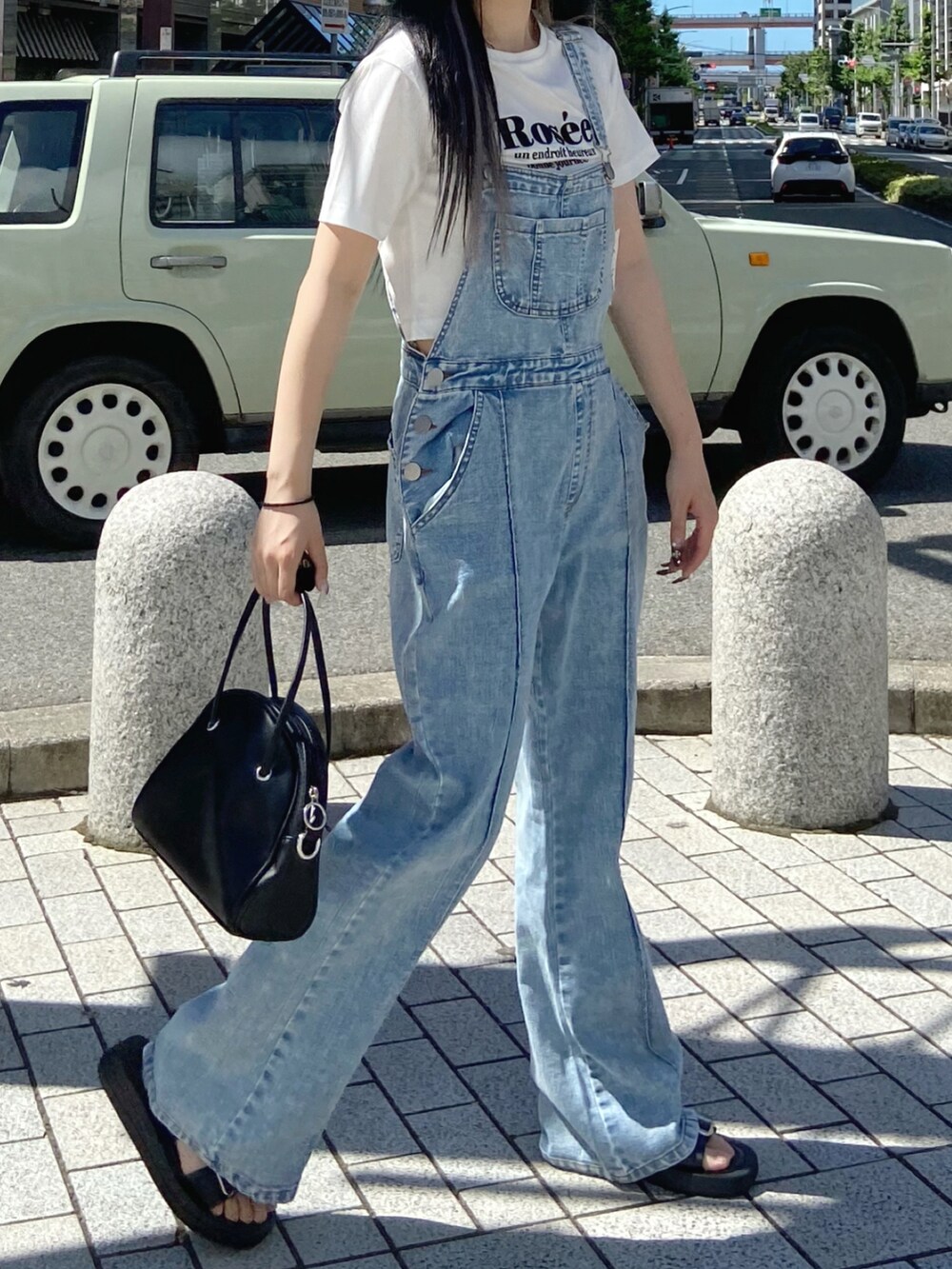 ブラック系のハンドバッグ、ホワイト系のTシャツ/カットソー、ブルー系のサロペット/オーバーオールを着用したレディースの夏コーディネートの2枚目の写真