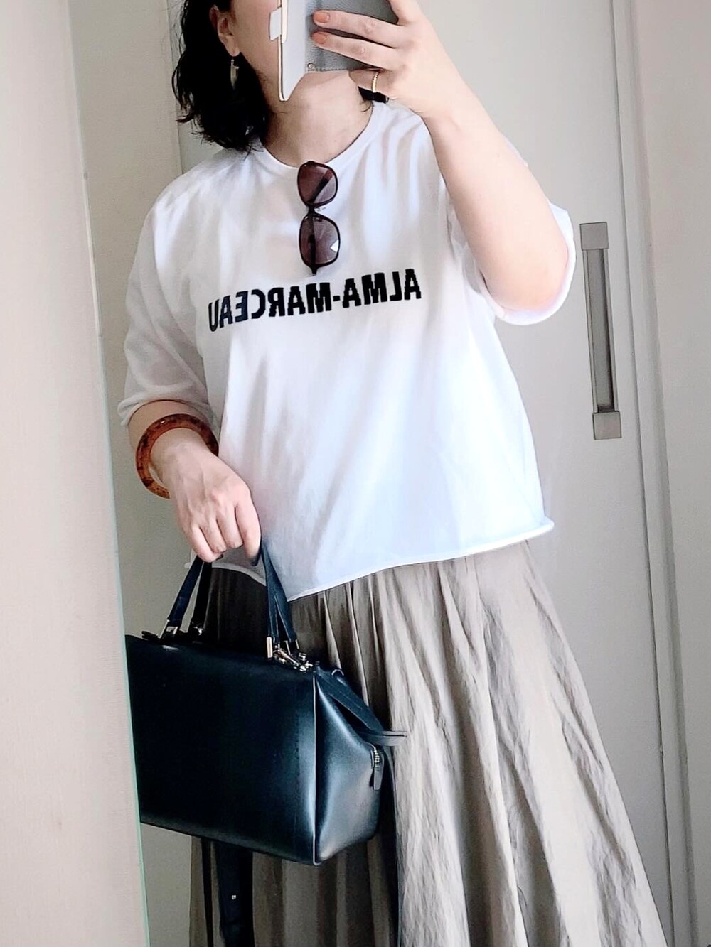 グリーン系のスカート、ブラック系のサンダル、ブラック系のショルダーバッグを着用したレディースの夏コーディネートの2枚目の写真