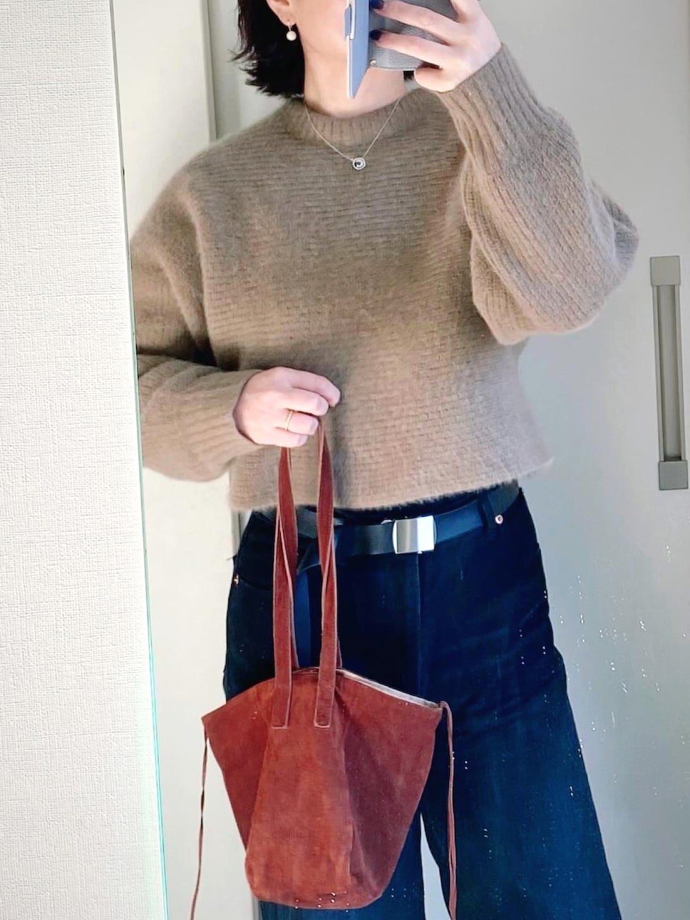 ブラック系のブーツ、ブラック系のデニムパンツ、ホワイト系のブルゾンを着用したレディースの冬コーディネートの2枚目の写真