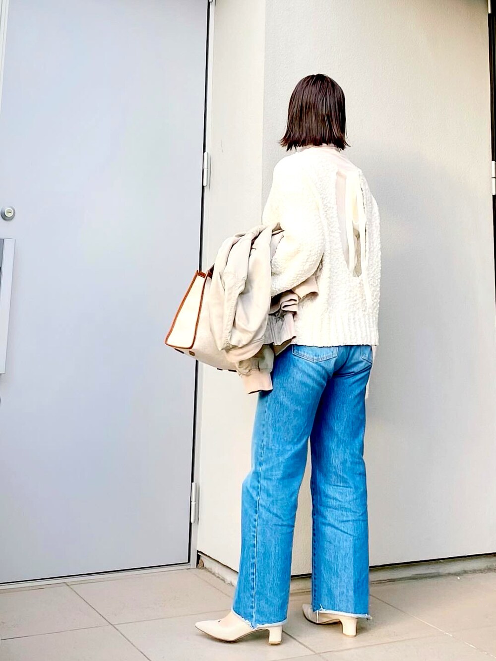 ホワイト系のTシャツ/カットソー、ホワイト系のニット/セーター、ブルー系のデニムパンツを着用したレディースの冬コーディネートの2枚目の写真