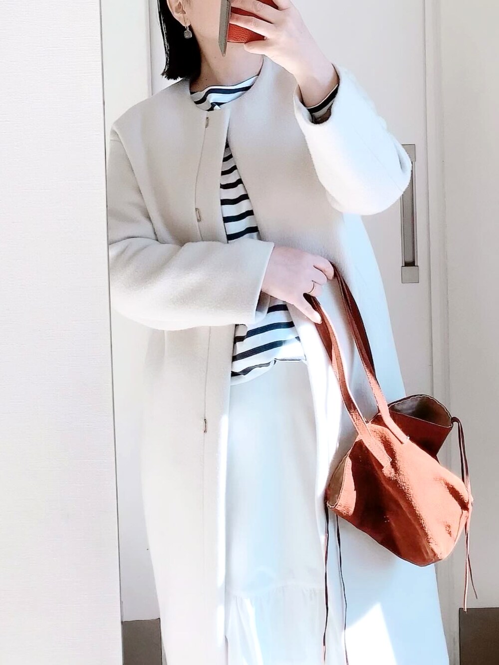 ホワイト系のスカート、ベージュ系のスニーカー、ブラウン系のバッグを着用したレディースの春コーディネートの2枚目の写真