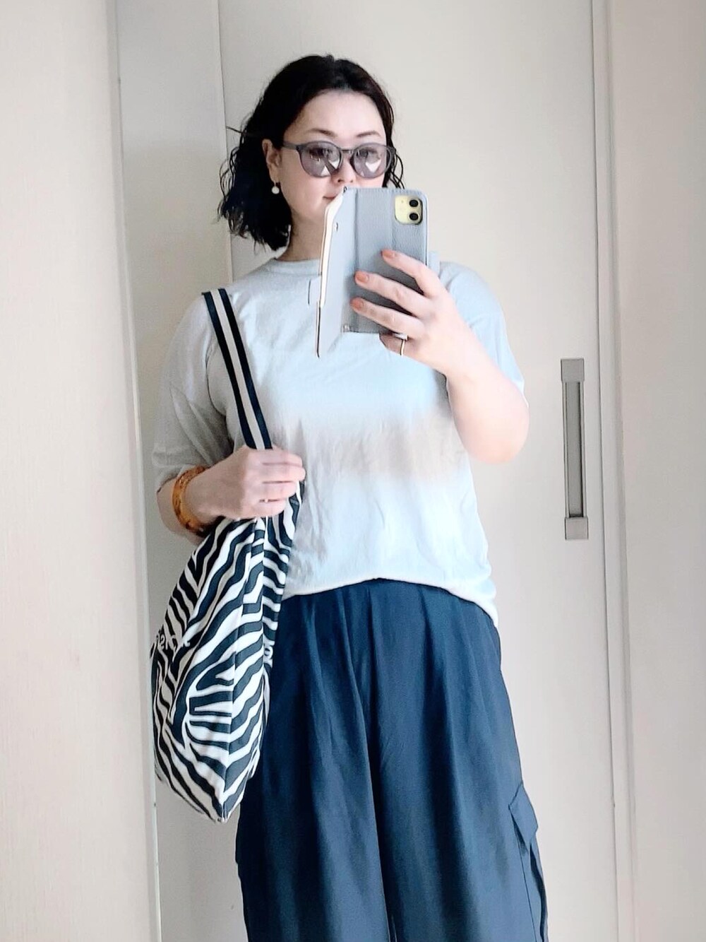 ブルー系のその他パンツ、シルバー系のニット/セーター、ブラック系のトートバッグを着用したレディースの夏コーディネートの2枚目の写真