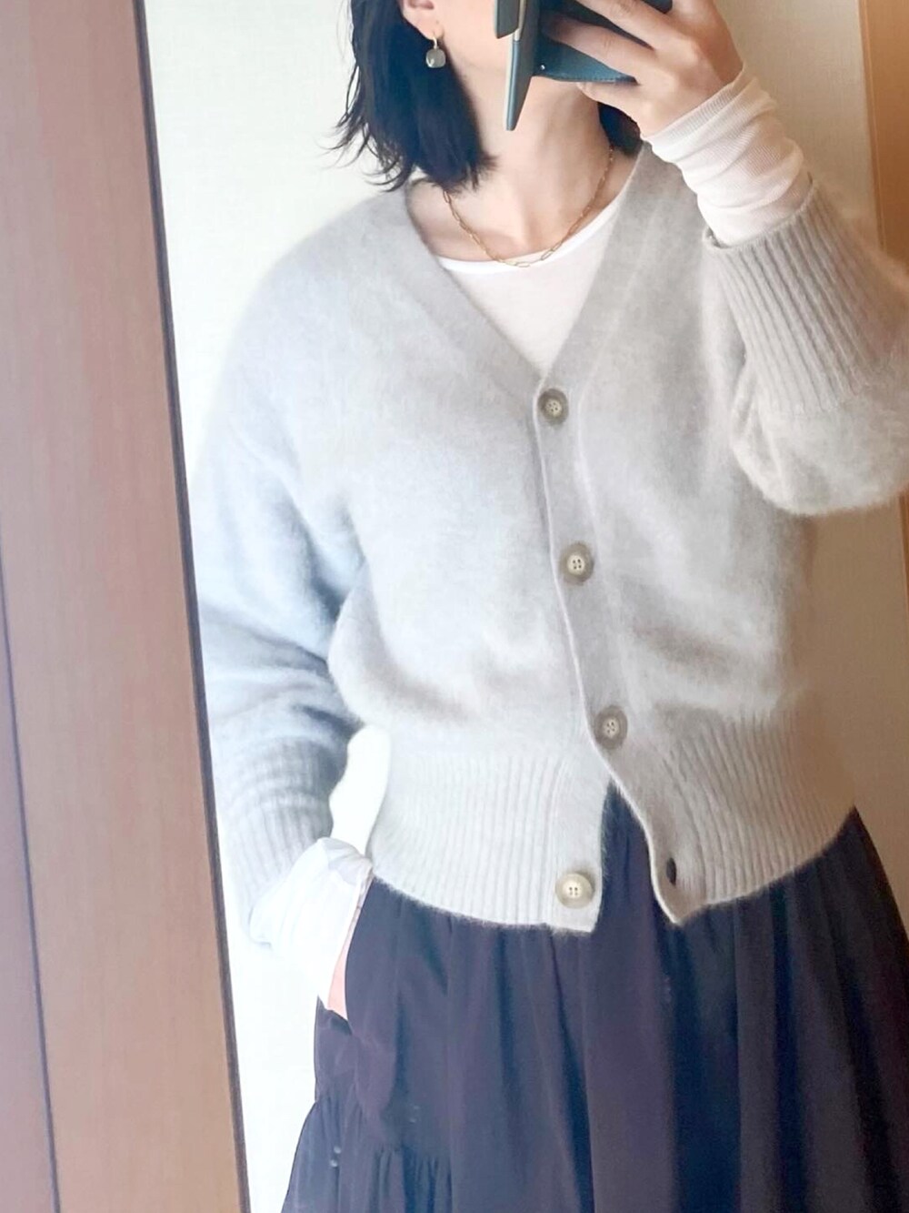 ホワイト系のTシャツ/カットソー、グレー系のカーディガン/ボレロ、ブラウン系のスカートを着用したレディースの冬コーディネートの2枚目の写真