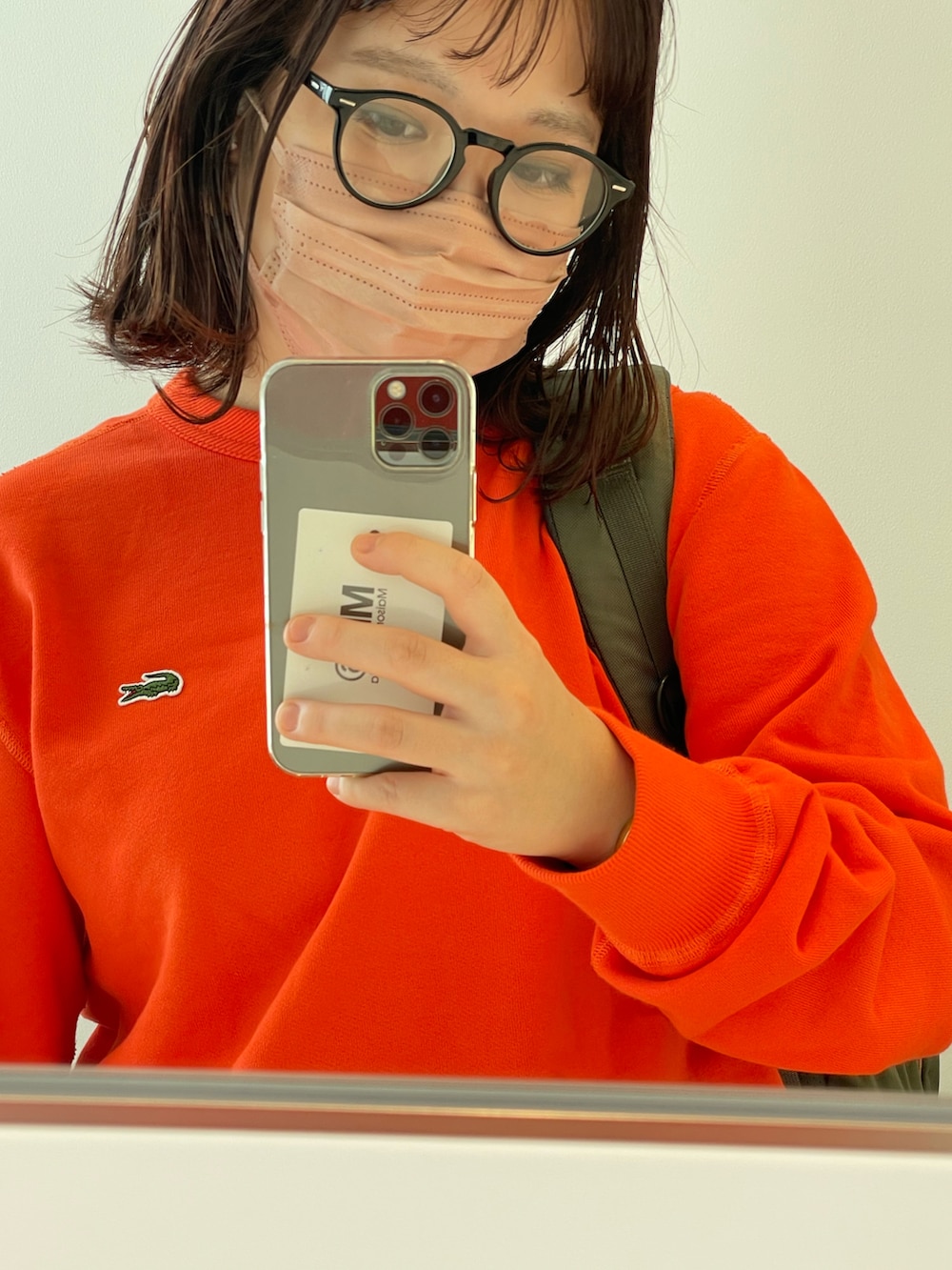 ブルー系のデニムパンツ、オレンジ系のスウェット、グリーン系のバックパック/リュックを着用したレディースの秋コーディネートの2枚目の写真