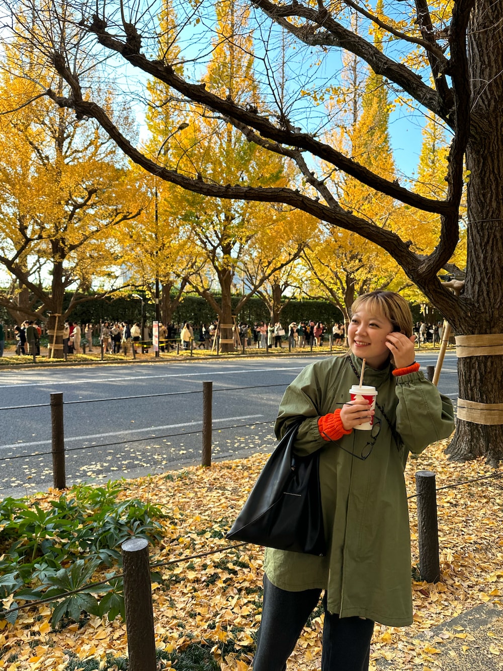 グリーン系のモッズコート、オレンジ系のニット/セーター、ブラック系のハンドバッグを着用したレディースの秋コーディネートの3枚目の写真