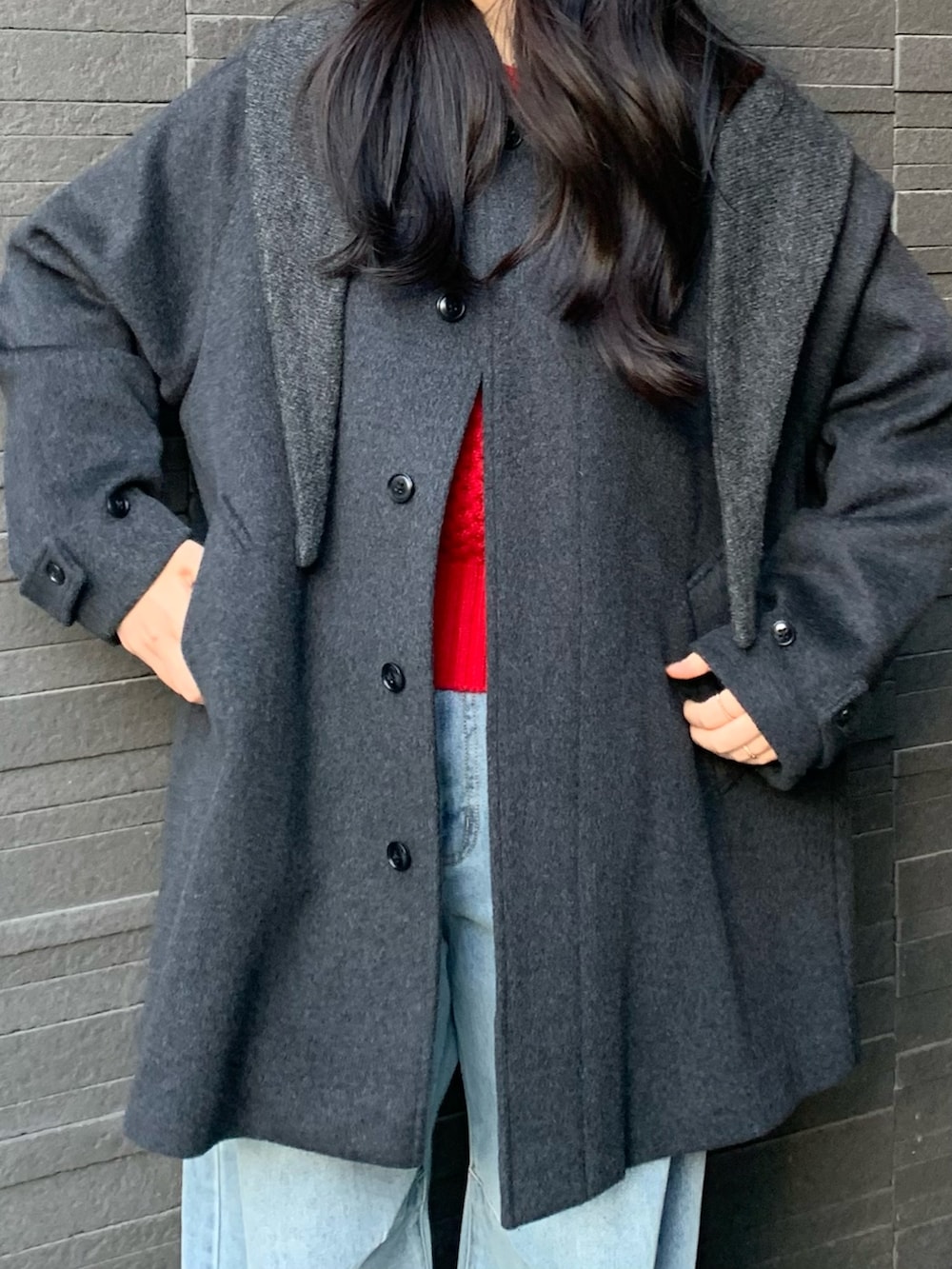 レッド系のニット/セーター、ブルー系のデニムパンツ、グレー系のステンカラーコートを着用したレディースの冬コーディネートの2枚目の写真