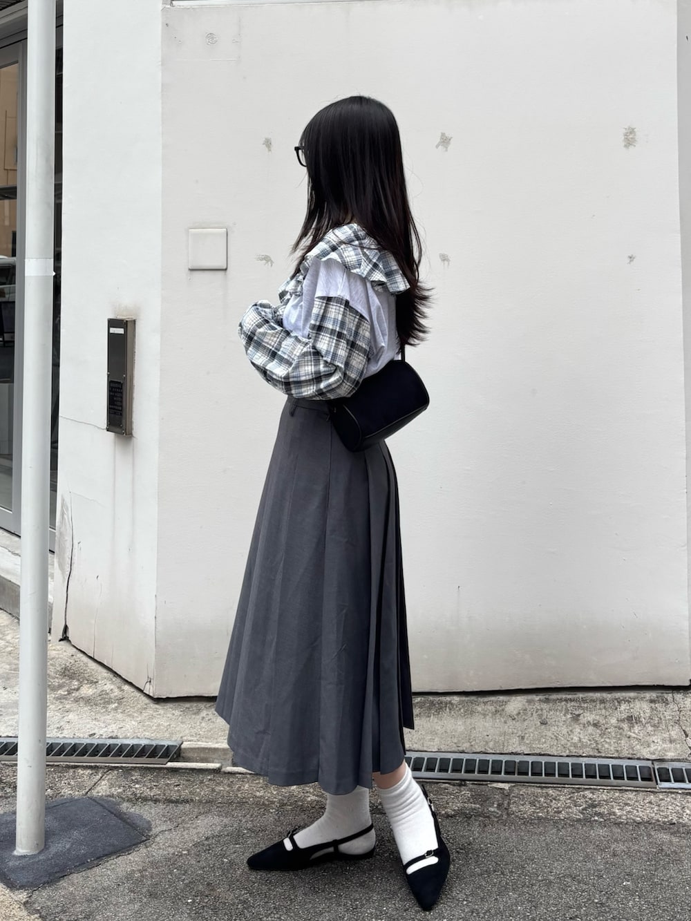 ブラック系のショルダーバッグ、ブラック系のサンダル、ベージュ系のTシャツ/カットソーを着用したレディースの秋コーディネートの2枚目の写真