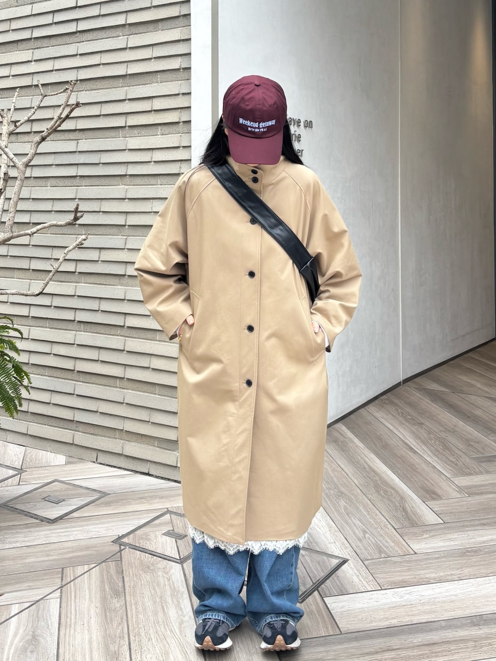 ブラック系のショルダーバッグ、ベージュ系のその他アウター、ホワイト系のスカートを着用したレディースの春コーディネートの2枚目の写真