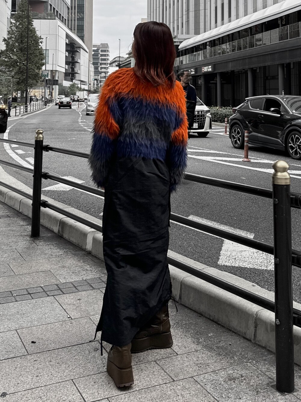 オレンジ系のニット/セーター、ブラック系のスカート、ブラウン系のブーツを着用したレディースの秋コーディネートの4枚目の写真