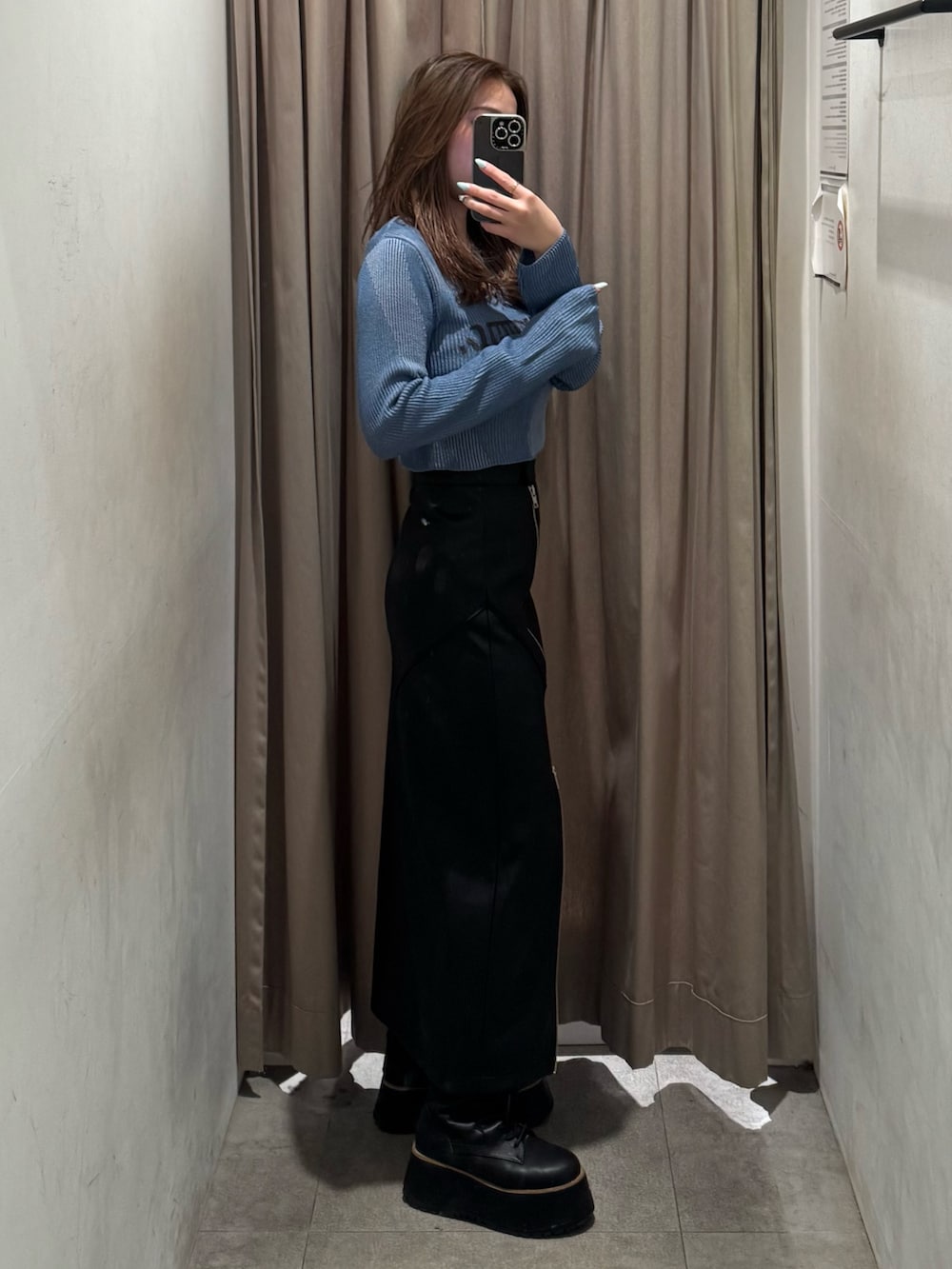 ブルー系のニット/セーター、ブラック系のスカート、ブラック系のブーツを着用したレディースの冬コーディネートの2枚目の写真