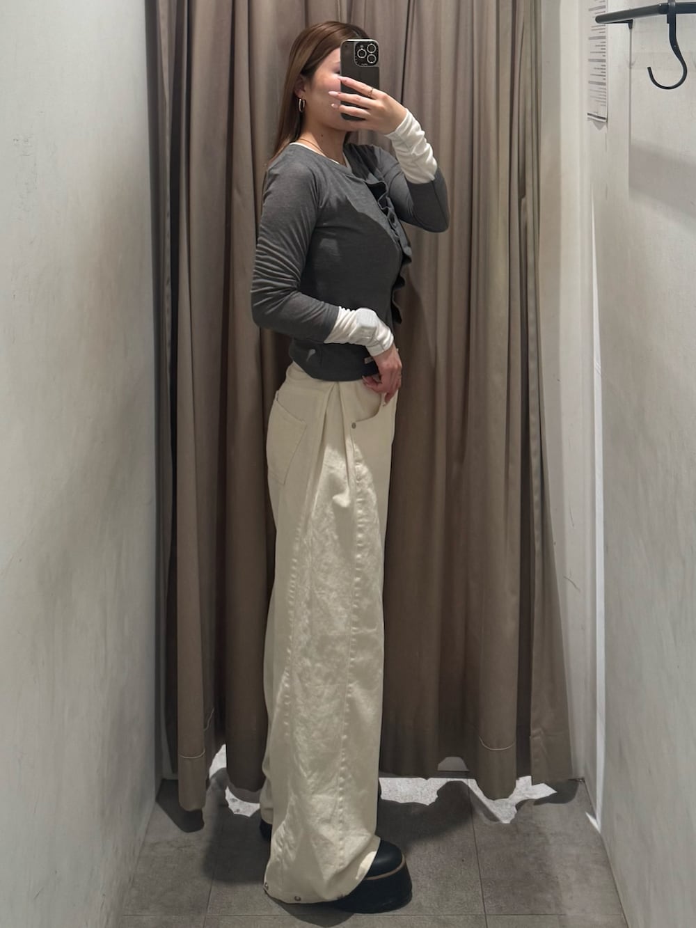 ホワイト系のデニムパンツ、グレー系のカーディガン/ボレロ、ブラック系のブーツを着用したレディースの春コーディネートの2枚目の写真