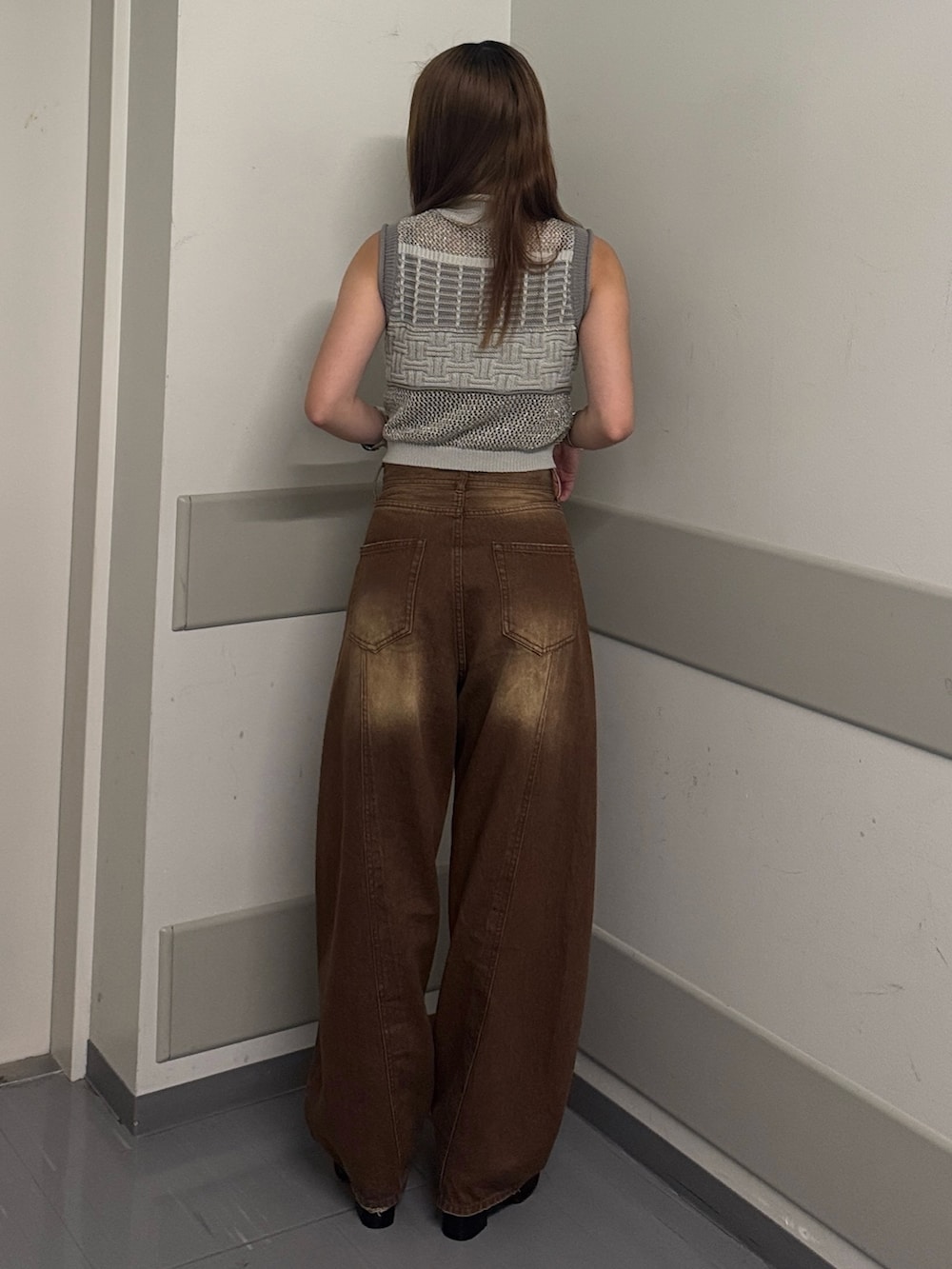 グレー系のタンクトップ、ブラウン系のデニムパンツ、ブラック系のサンダルを着用したレディースの夏コーディネートの3枚目の写真