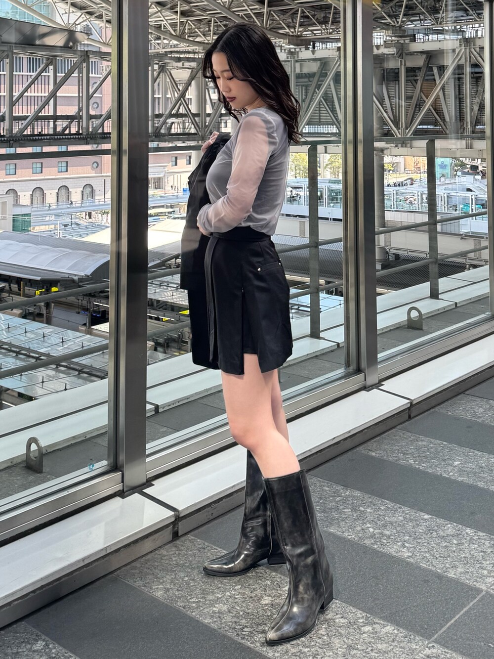 グレー系のTシャツ/カットソー、ブラック系のスカート、ブラウン系のブーツを着用したレディースの春コーディネートの2枚目の写真