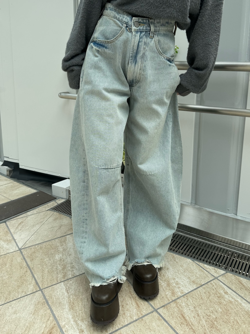 グレー系のニット/セーター、ブルー系のデニムパンツ、ブラウン系のブーツを着用したレディースの秋コーディネートの6枚目の写真