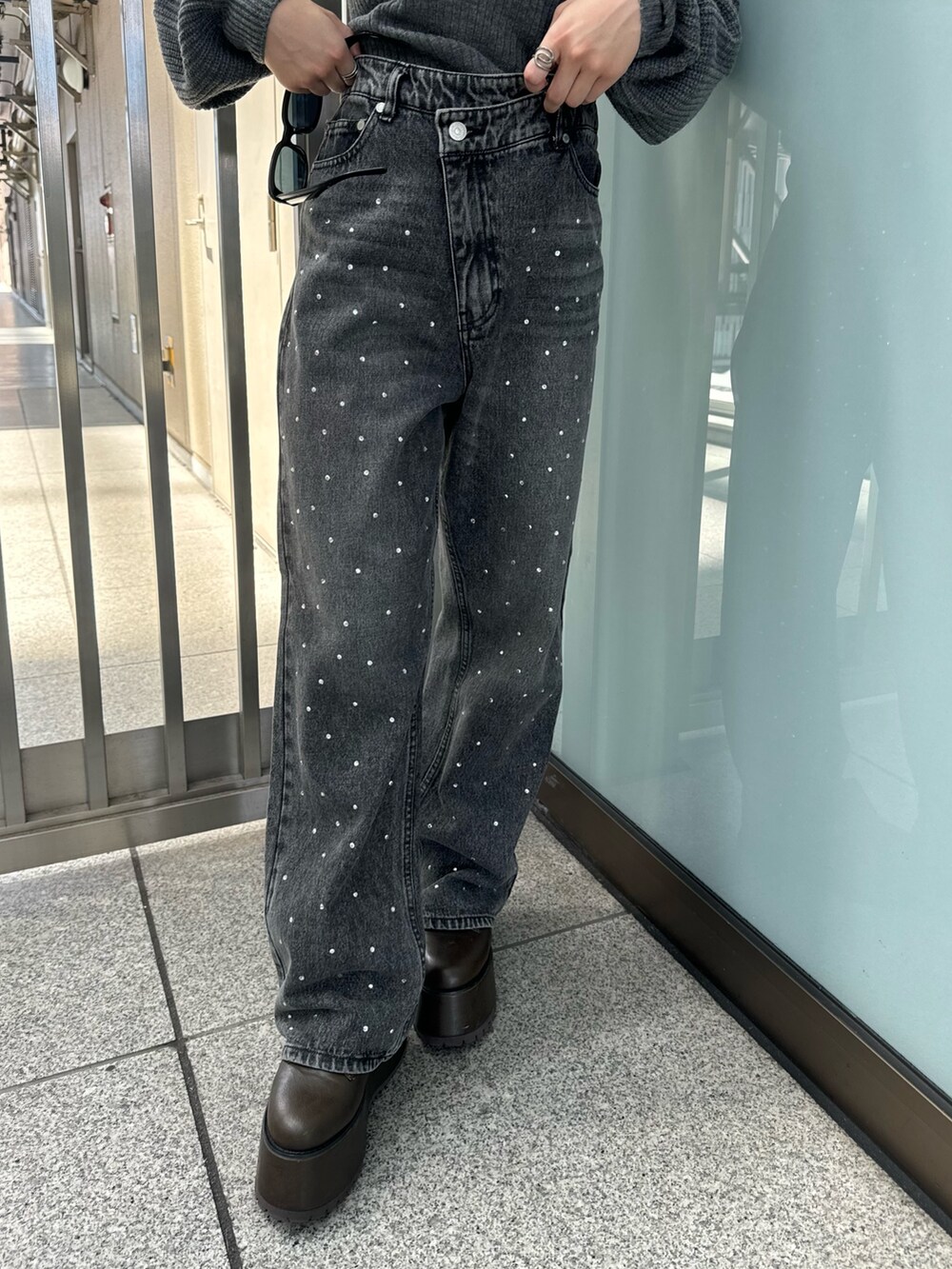 グレー系のニット/セーター、ブラック系のデニムパンツ、ブラウン系のブーツを着用したレディースの秋コーディネートの8枚目の写真