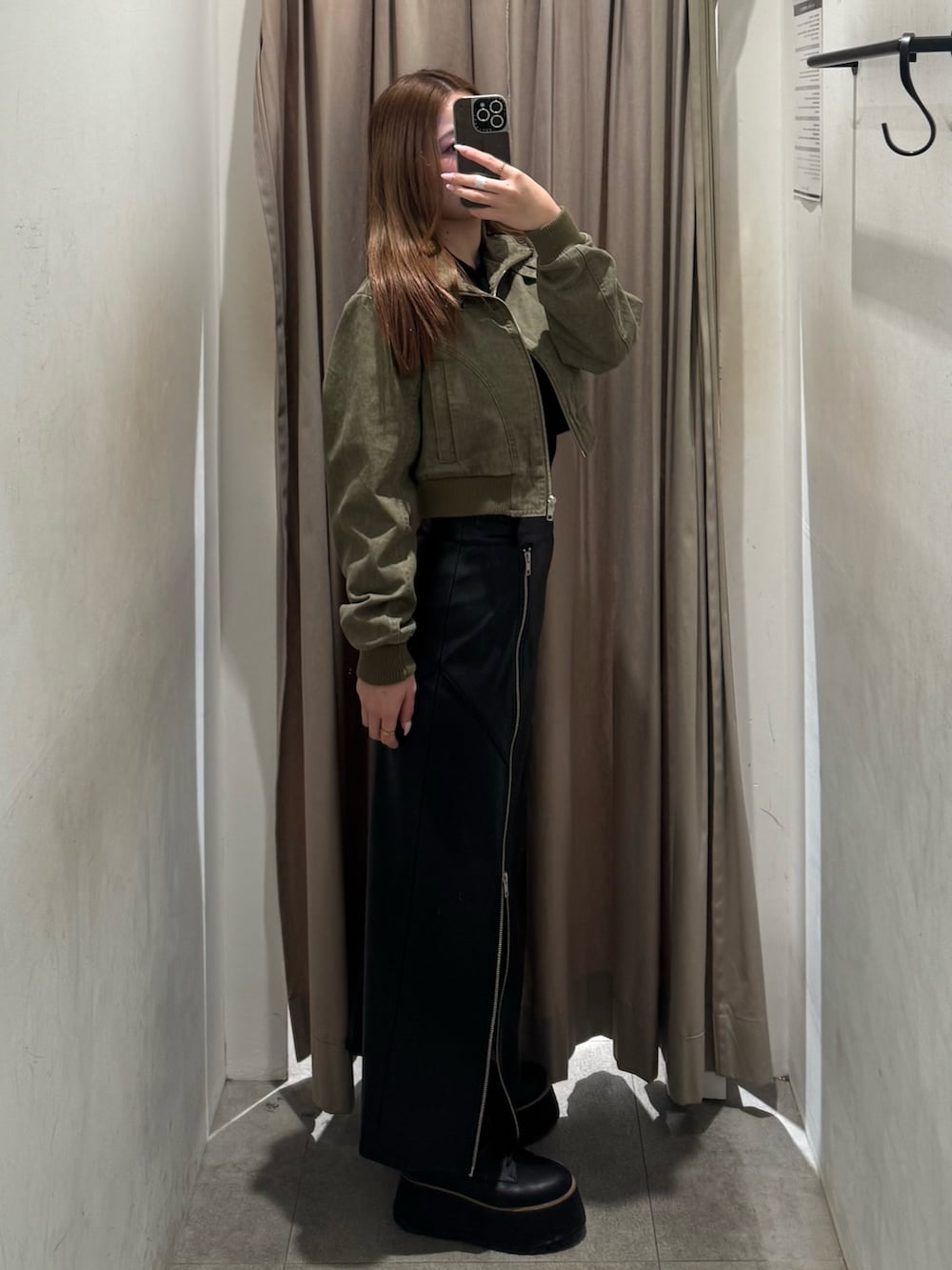 ブラック系のスカート、グリーン系のブルゾン、ブラック系のブーツを着用したレディースの春コーディネートの2枚目の写真