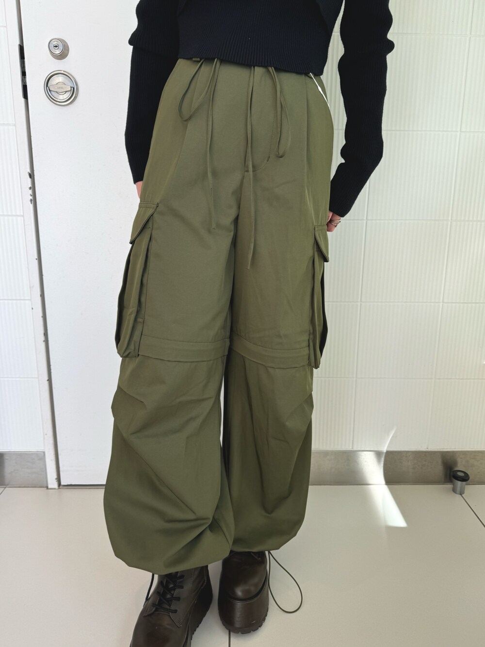 ブラック系のニット/セーター、ベージュ系のカーゴパンツ、ブラウン系のブーツを着用したレディースの秋コーディネートの6枚目の写真