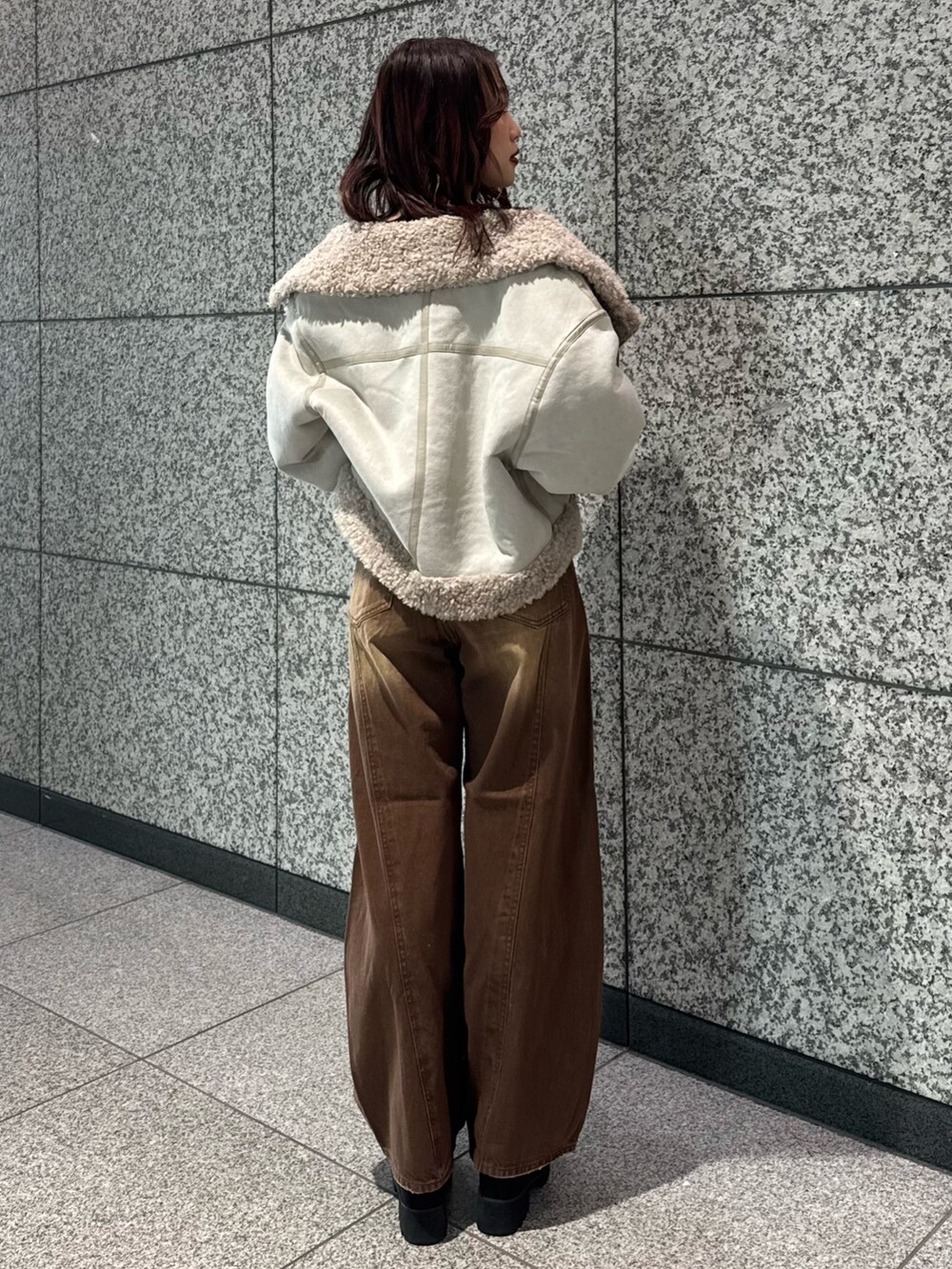 ブラック系のニット/セーター、ホワイト系のムートンコート、ブラウン系のデニムパンツを着用したレディースの冬コーディネートの3枚目の写真