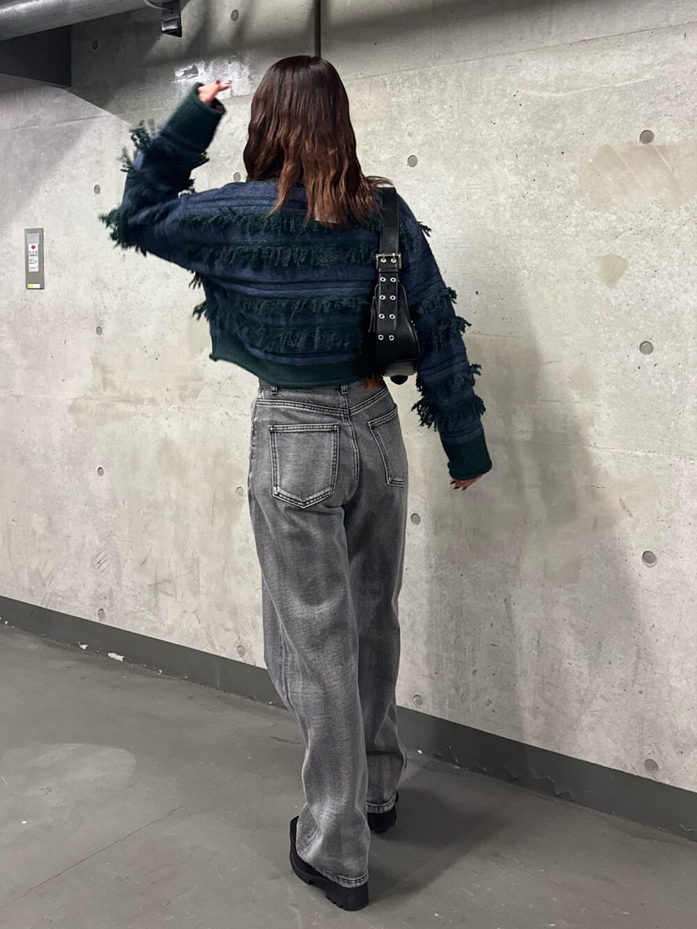 グリーン系のニット/セーター、ブラック系のデニムパンツ、ブラック系のブーツを着用したレディースの冬コーディネートの3枚目の写真