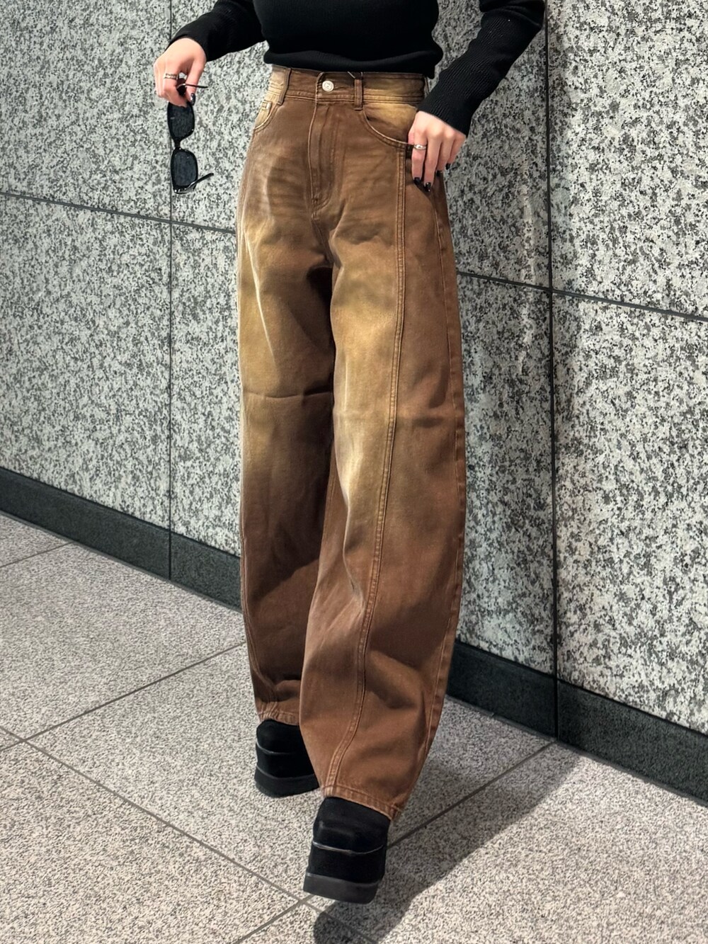 ブラック系のニット/セーター、ブラウン系のデニムパンツ、ブラック系のブーツを着用したレディースの冬コーディネートの5枚目の写真