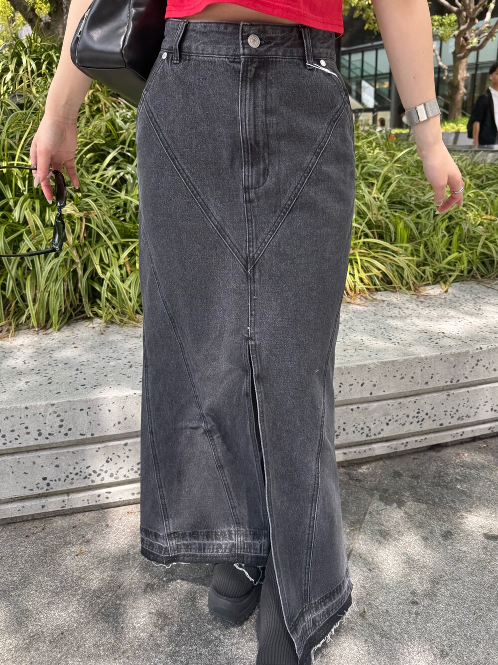 レッド系のTシャツ/カットソー、ブラック系のデニムスカート、ブラック系のブーツを着用したレディースの春コーディネートの6枚目の写真