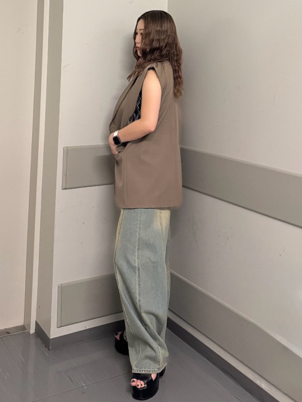 ブラック系のタンクトップ、ブラウン系のベスト、ブルー系のデニムパンツを着用したレディースの夏コーディネートの2枚目の写真