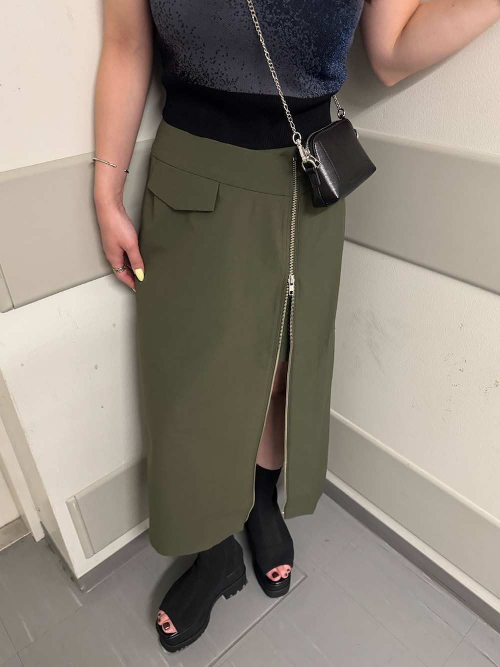 ブラック系のタンクトップ、グリーン系のスカート、ブラック系のサンダルを着用したレディースの夏コーディネートの6枚目の写真