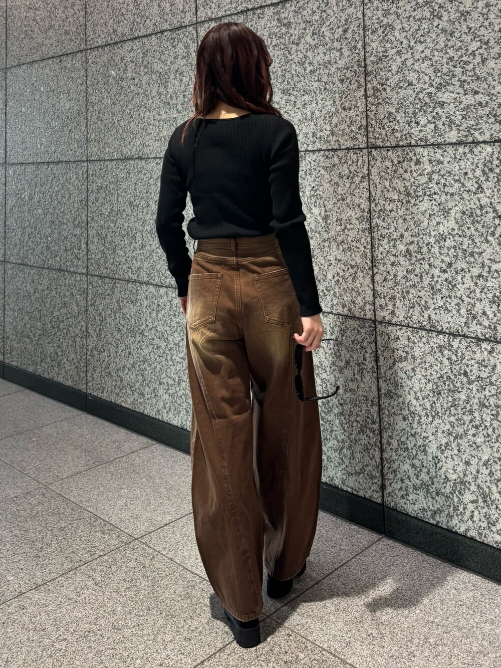 ブラック系のニット/セーター、ブラウン系のデニムパンツ、ブラック系のブーツを着用したレディースの冬コーディネートの3枚目の写真