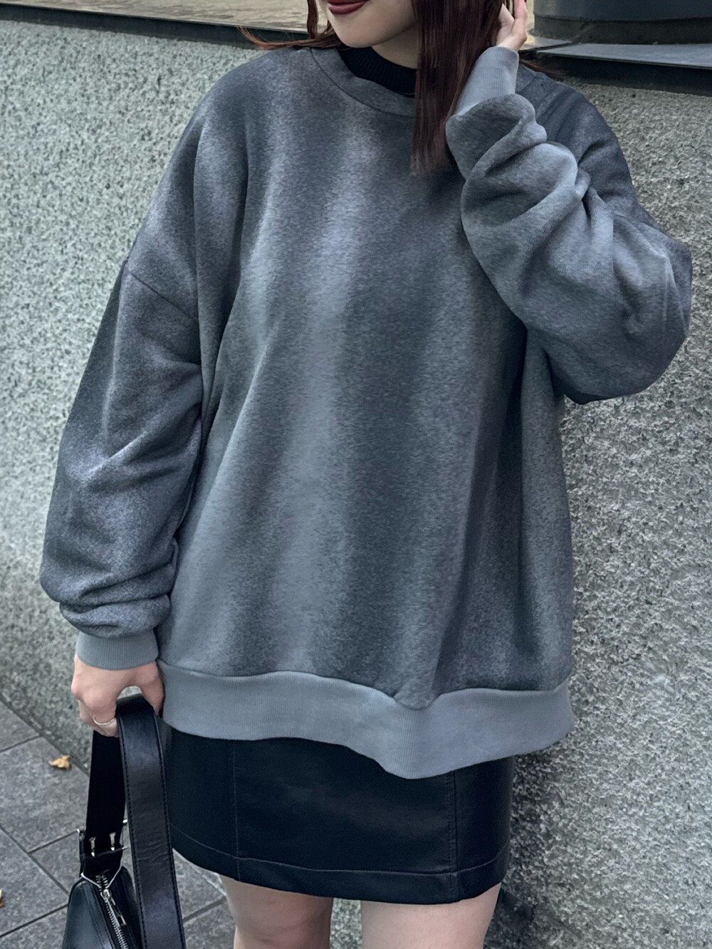 グレー系のスウェット、ブラック系のスカート、ブラック系のハンドバッグを着用したレディースの秋コーディネートの5枚目の写真