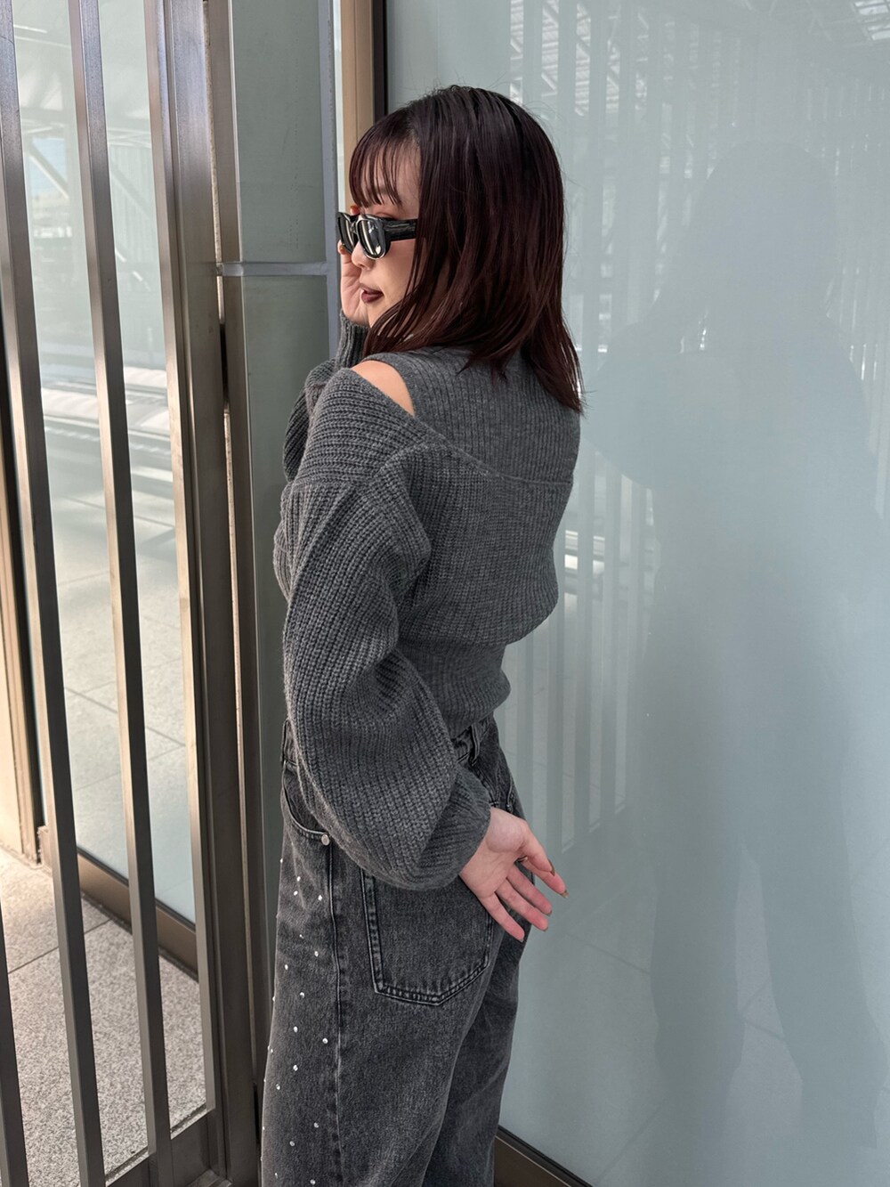 グレー系のニット/セーター、ブラック系のデニムパンツ、ブラウン系のブーツを着用したレディースの秋コーディネートの5枚目の写真