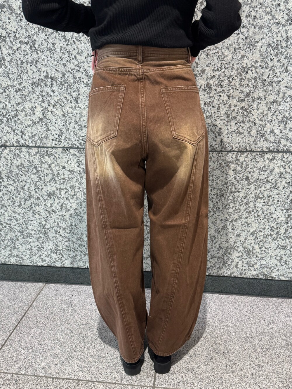 ブラック系のニット/セーター、ブラウン系のデニムパンツ、ブラック系のブーツを着用したレディースの冬コーディネートの6枚目の写真