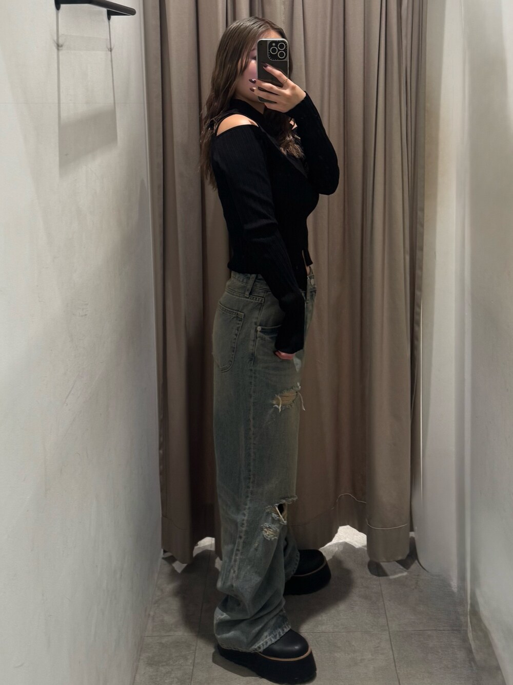 ブルー系のデニムパンツ、ブラック系のニット/セーター、ブラック系のブーツを着用したレディースの秋コーディネートの2枚目の写真