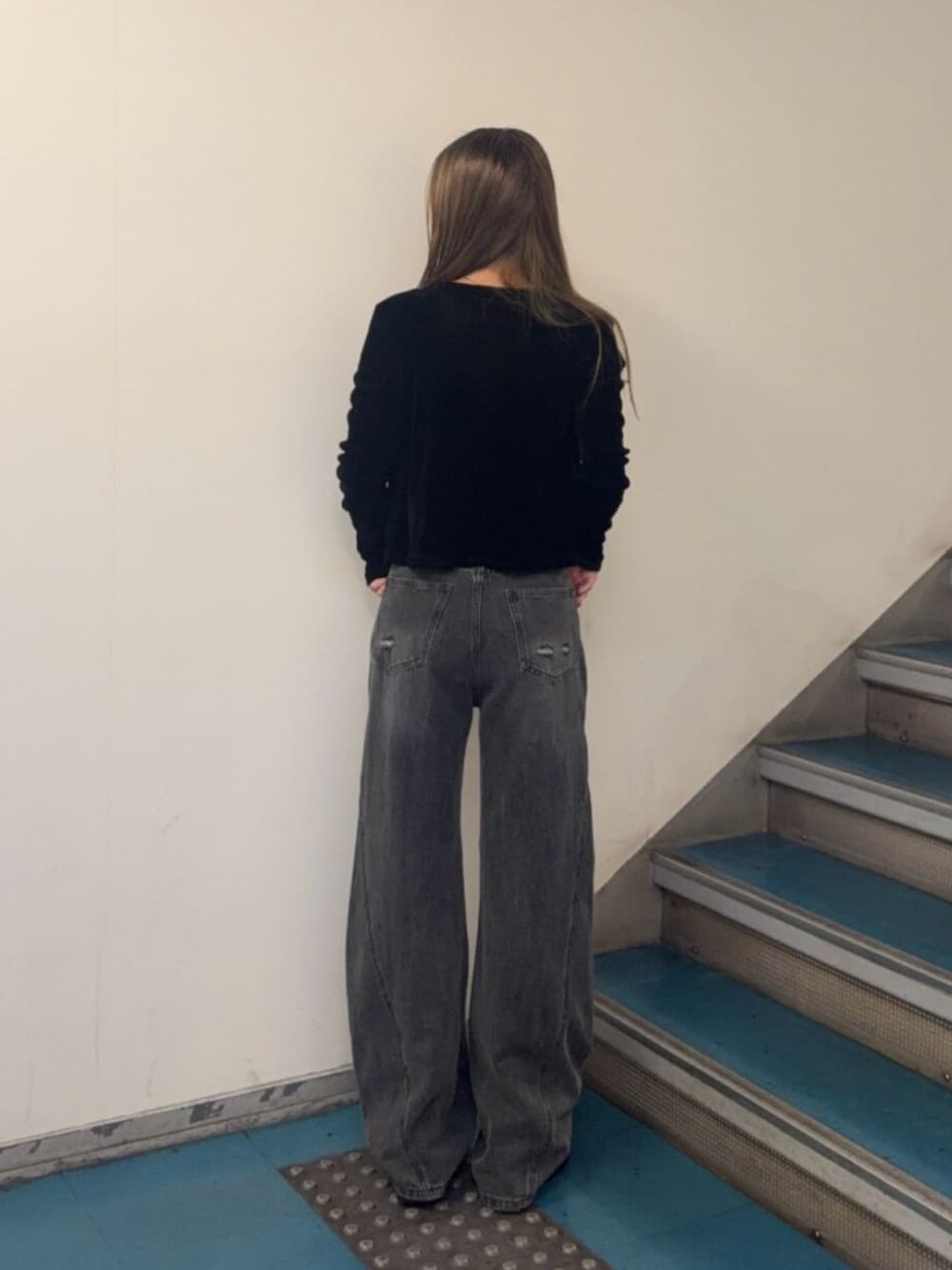 グレー系のデニムパンツ、ブラック系のブーツ、ブラック系のアンサンブルを着用したレディースの秋コーディネートの3枚目の写真